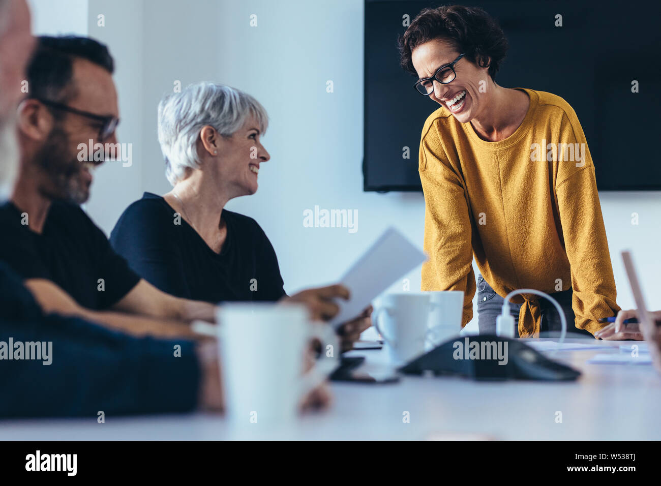 Group of businesspeople smiling during a meeting in conference room. Business people having casual discussion during meeting in board room. Stock Photo