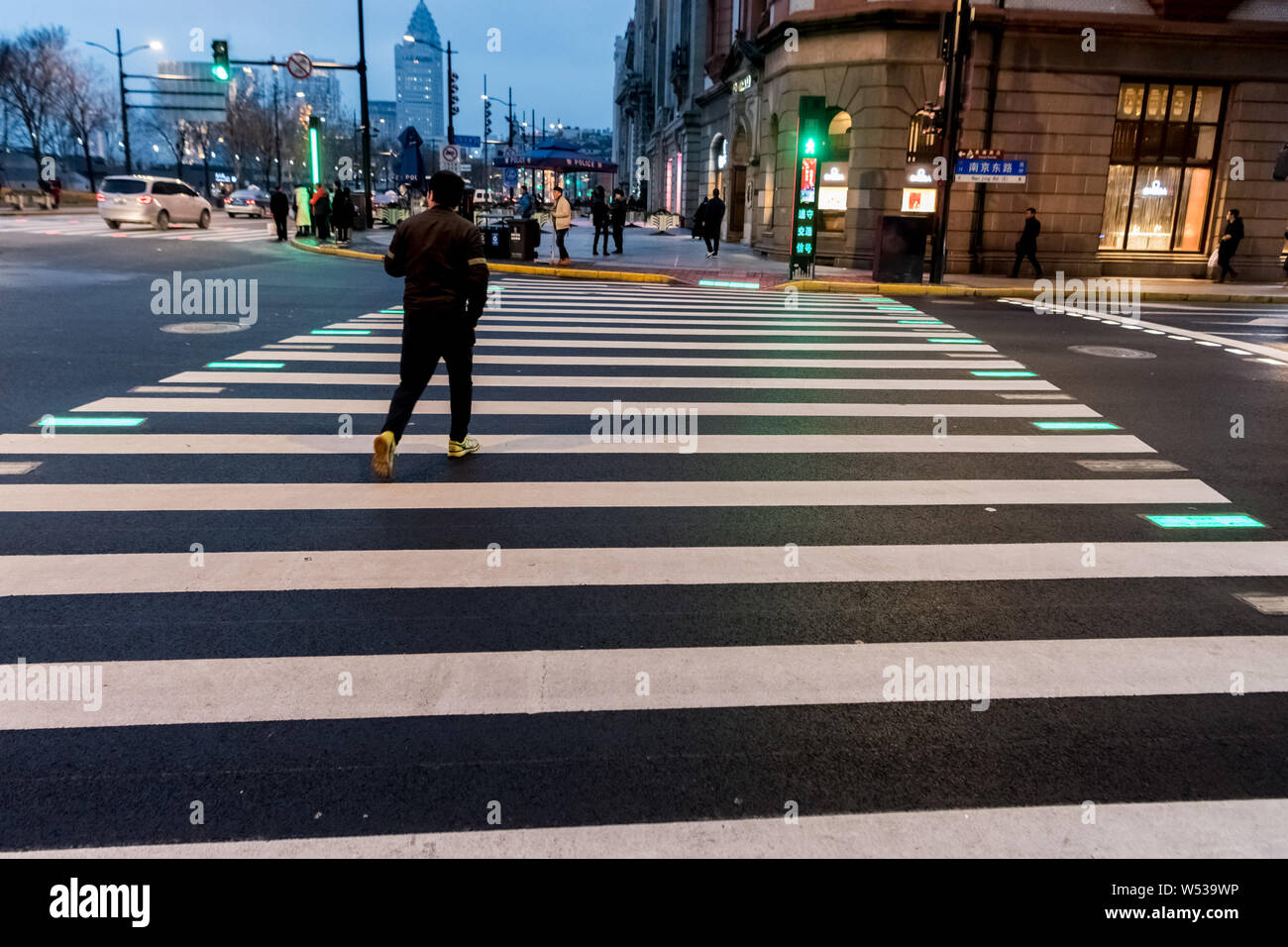 A Pedestrian Walks Across A Zebra Crossing Illuminated By LED Lights In A Pedestrian Walks Across A Zebra Crossing Illuminated By LED Lights In