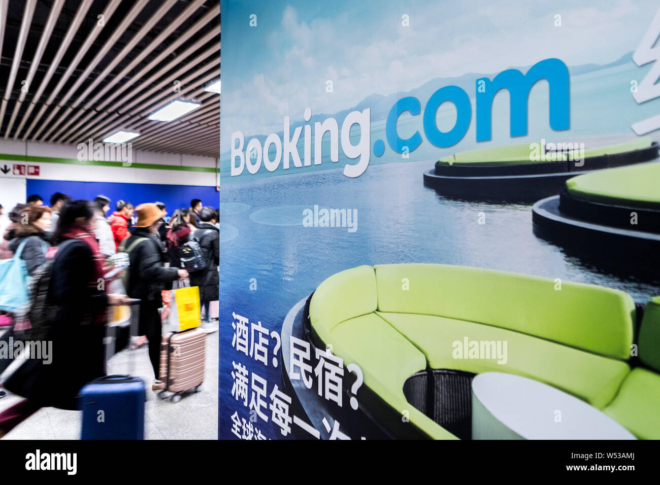 Passengers walk past an advertisement for online hotel reservation site Booking.com at a metro station in Shanghai, China, 29 December 2018.   Booking Stock Photo