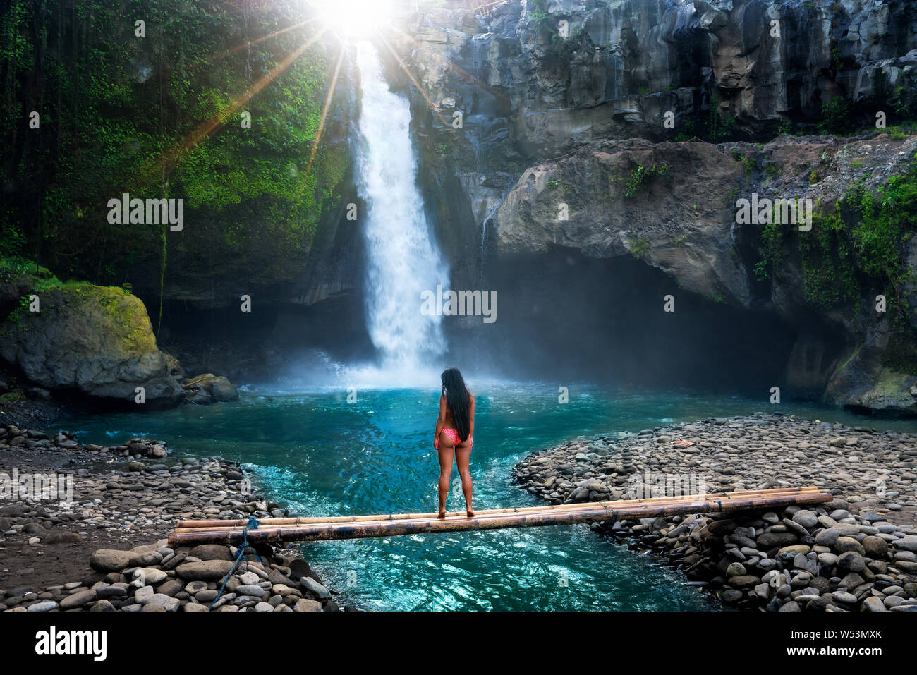 Beautiful woman enjoy amazing waterfall hidden in tropical jungle at sunrise. Amazing nature landscape. Concept lifestyle and eco tourism. Stock Photo