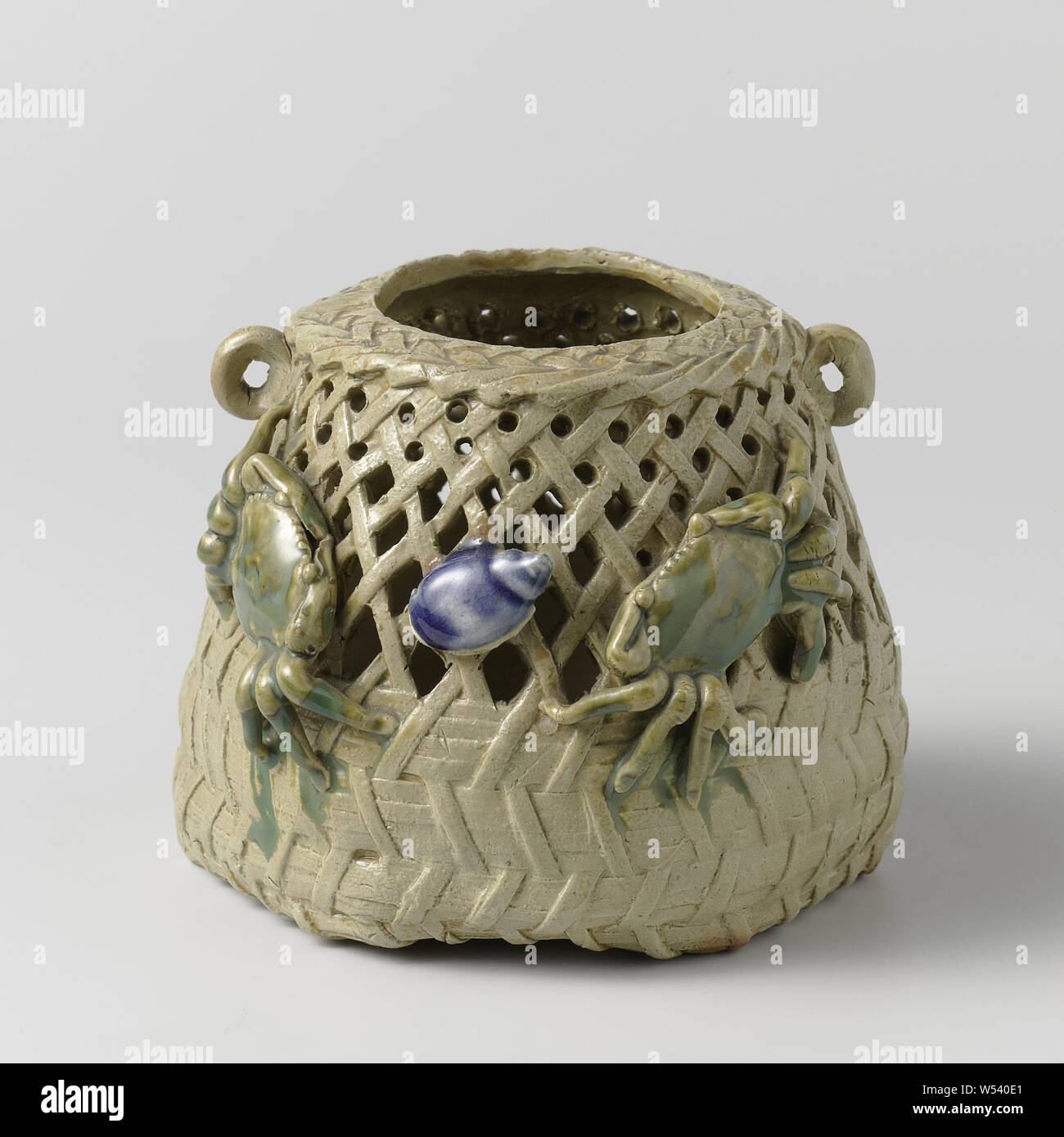 Pierced jar in the shape of a basket with two crabs and a conch, Pot of stoneware in the shape of a basket with an openwork wall and two small, raised ears, painted on the glaze in blue and green. On the outside, two modeled crabs and a shell. Six holes in the bottom, molluscs (shell, snail shell etc.), anonymous, Japan, c. 1875 - c. 1899, Edo-period (1600-1868), stoneware, glaze, vitrification, h 9.3 cm d 8.3 cm d 12.1 cm d 11.2 cm Stock Photo