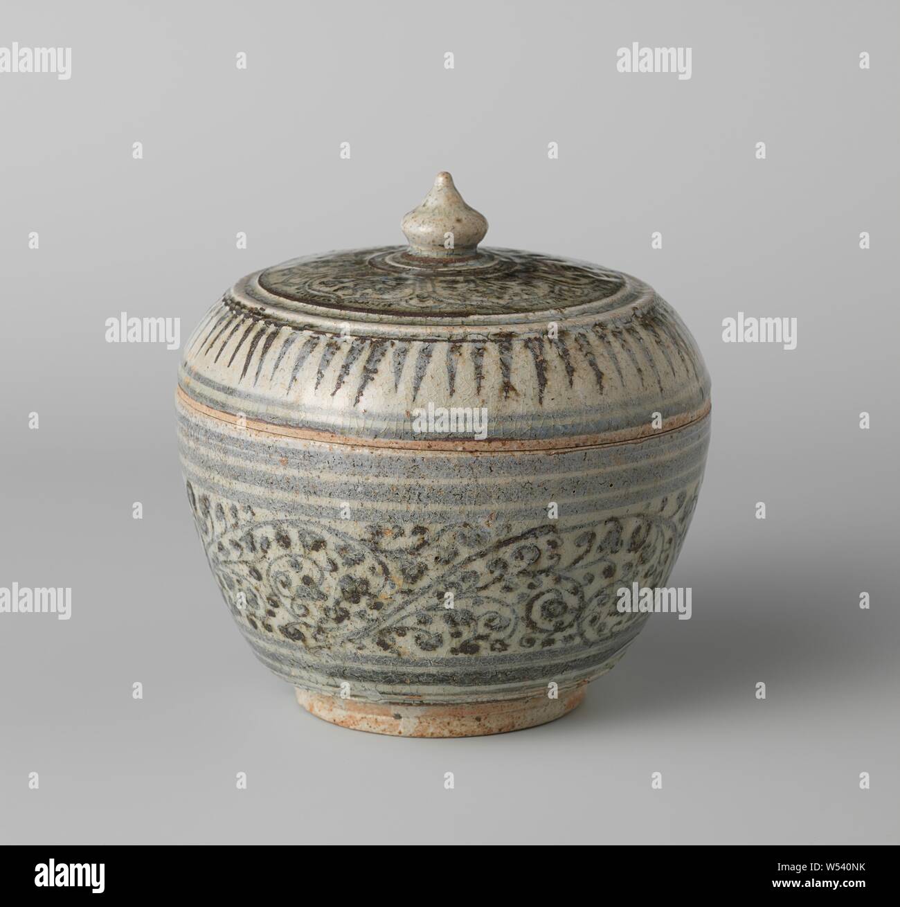 Covered jar with floral scrolls, Lid of stoneware jar, painted in underglaze blue. On the lid a band with petal-shaped compartments with flowering plants. Edge-pointed leaf motifs depending on the edge. The glaze is slightly gray. Blue White., anonymous, Thailand, c. 1700 - c. 1799, stoneware, glaze, cobalt (mineral), vitrification, h 6.3 cm × d 16 cm Stock Photo