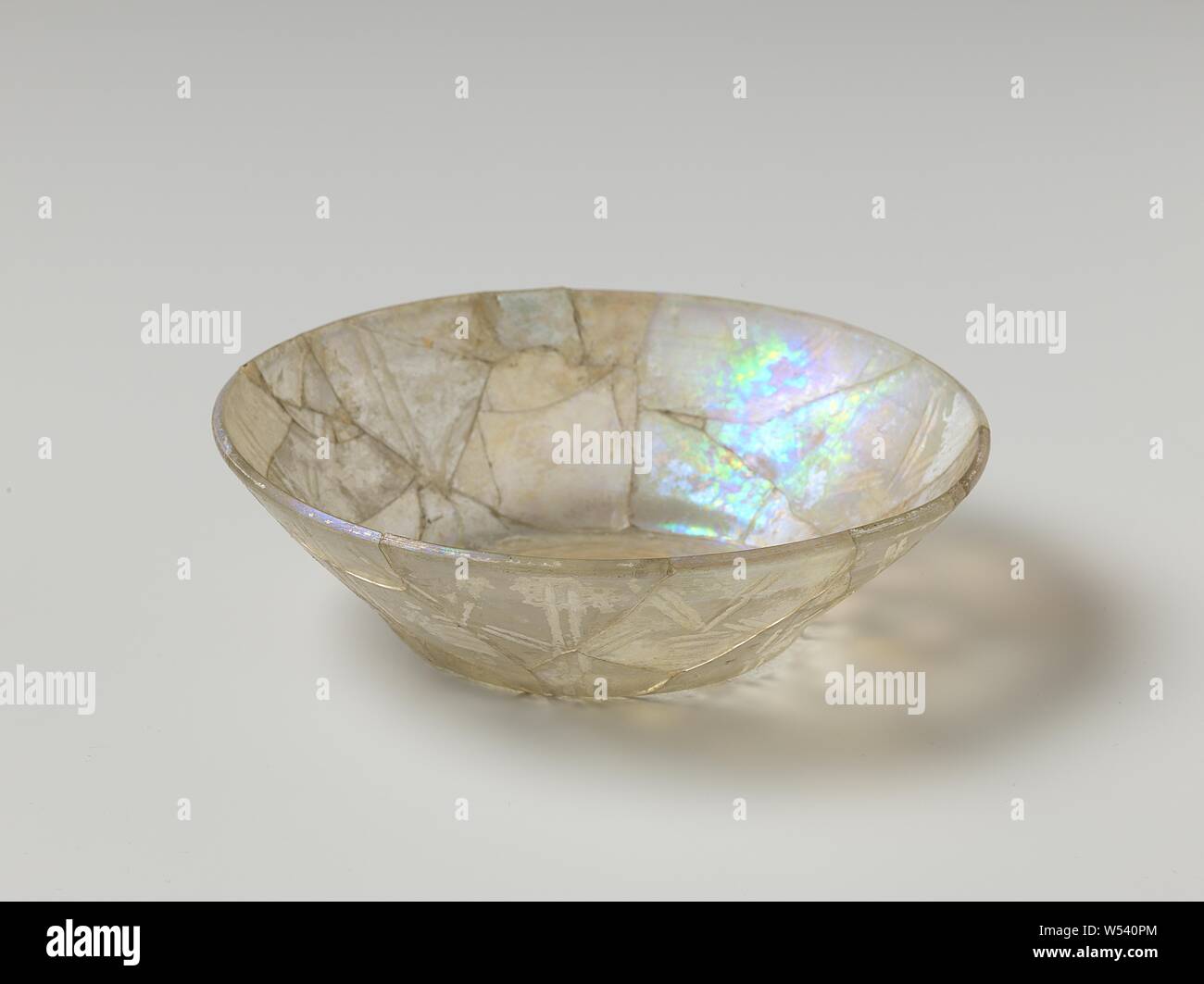 Bowl of glass, Bowl, concave, translucent, iridescent glass. Decorated on the outside with simple patterns carved into broad double lines. (broken and glued). Follows the shape of an earthenware bowl., anonymous, Nishapur (possibly), c. 900 - c. 1100, glass, h 5.5 cm × d 20 cm Stock Photo