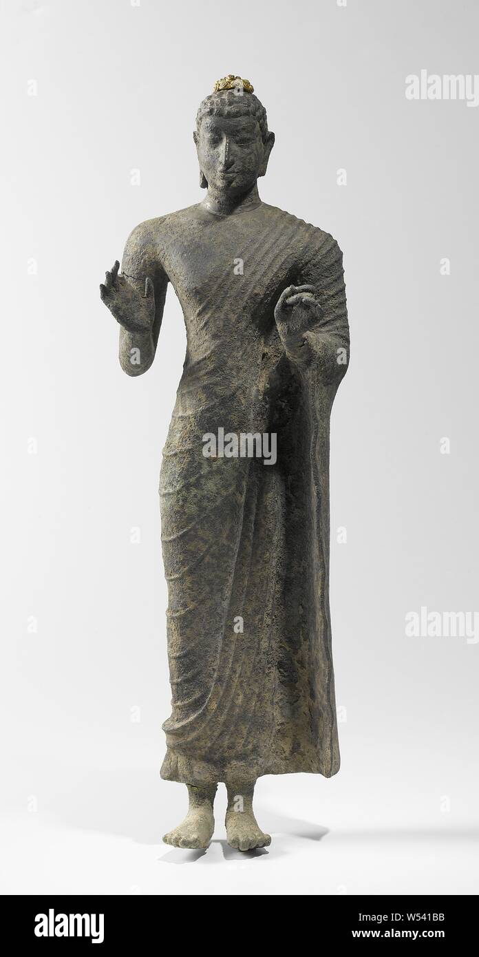 Standing Buddha, Buddha, right foot is created, right hand in abhaya mudra, the left in witarka mudra. The statue is made of bronze around a cement-like core, founder or Buddhism, anonymous, Oost-Java, c. 700 - c. 800, bronze (metal), gold (metal), h 42.0 cm × w 12.0 cm × w 3.786 kg × w 8 Stock Photo