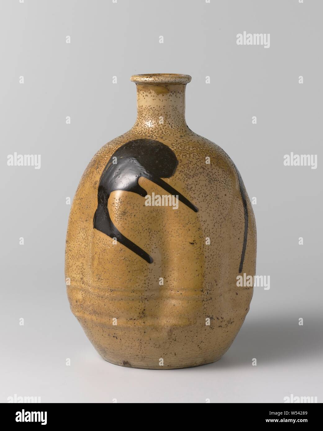 Ovoid sake bottle with a yellow glaze and brown marks, Egg shaped sake bottle made of stoneware with indented walls, covered with a yellow glaze and painted in brown. Four brown spots on the belly. Old label on the bottom with 'W504'., anonymous, Japan, c. 1750 - c. 1850, Edo-period (1600-1868), stoneware, glaze, vitrification, h 21.2 cm d 4.5 cm d 14.8 cm d 9 cm Stock Photo