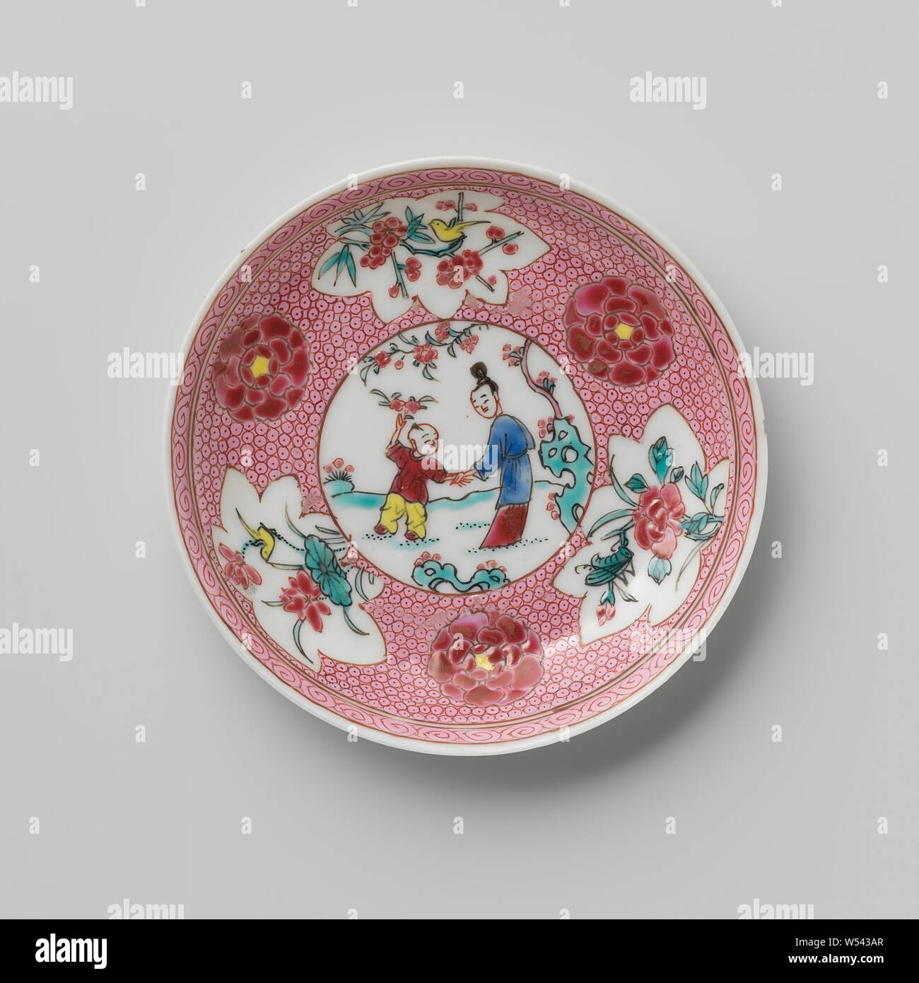 Saucer with a Chinese lady and boy in a landscape and flower sprays on diaper pattern, Porcelain dish with a spreading wall, painted on the glaze in blue, red, pink, green, yellow and black. On the plate of the dish a medallion with a Chinese lady and a boy in a landscape with trees and rocks, the medallion napkin with three flowers and three cartouches with a bird or insect on a flower branch (prunus, peony, lotus), the inner edge with a curled band. Famille rose., anonymous, China, c. 1725 - c. 1749, Qing-dynasty (1644-1912) / Yongzheng-period (1723-1735) / Qianlong-period (1736-1795 Stock Photo