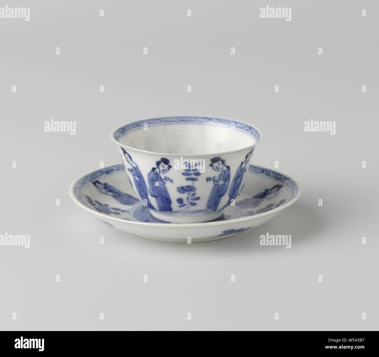 Cup and saucer with Chinese ladies and flower sprays, Porcelain cup and saucer, painted in underglaze blue. On the wall of the head two ladies with a twig in hand opposite each other with a plant in between them, at the bottom a sitting lady in front of a fence near a plant, the inner edge with zigzag pattern. On the plate of the dish a medallion with a seated lady at a rock with a plant, around the medallion two ladies with a twig in hand by a flower branch, the edge with a zigzag pattern, the back with four valuables (pearl, artemisia leaf, shell, music stone). Saucer marked on the underside Stock Photo