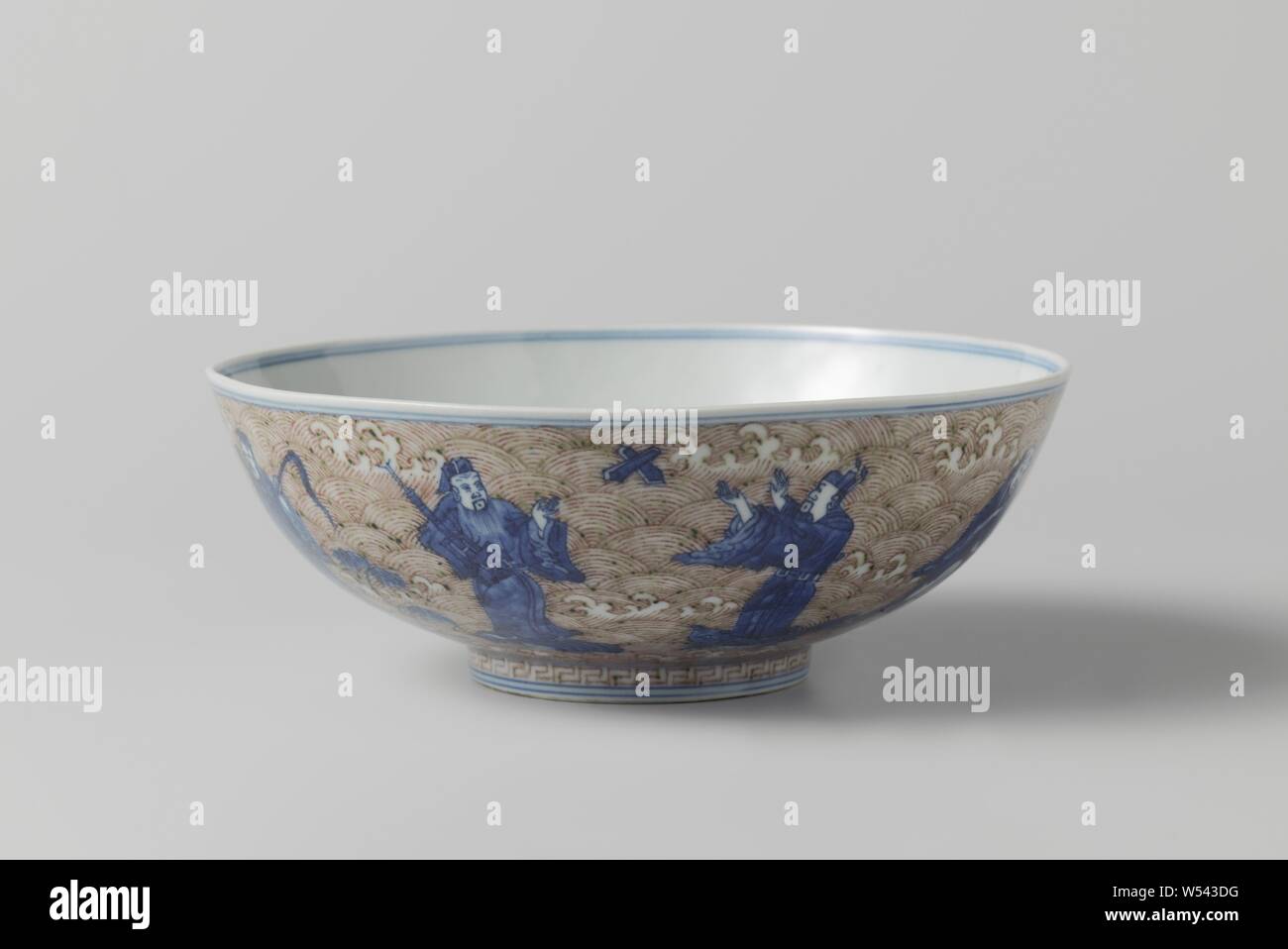Bowl with the eight immortals and Shoulao, Bowl of porcelain with flared wall, painted in underglaze blue and red. On the outside the Eight Immortals standing on marine animals, against a backdrop of foamy waves, on the bottom Shoulao with a deer with a mushroom in its mouth against a backdrop of foamy waves and clouds, a decorative edge with a meander motif around the foot ring. On the underside the six-character mark Chenghua in a double circle and an old label with 'Marked Ching-Hua period 1465-1488 1888 A. Trapnell' on it. Underglaze blue with copper red., anonymous, China, c. 1875 - c Stock Photo