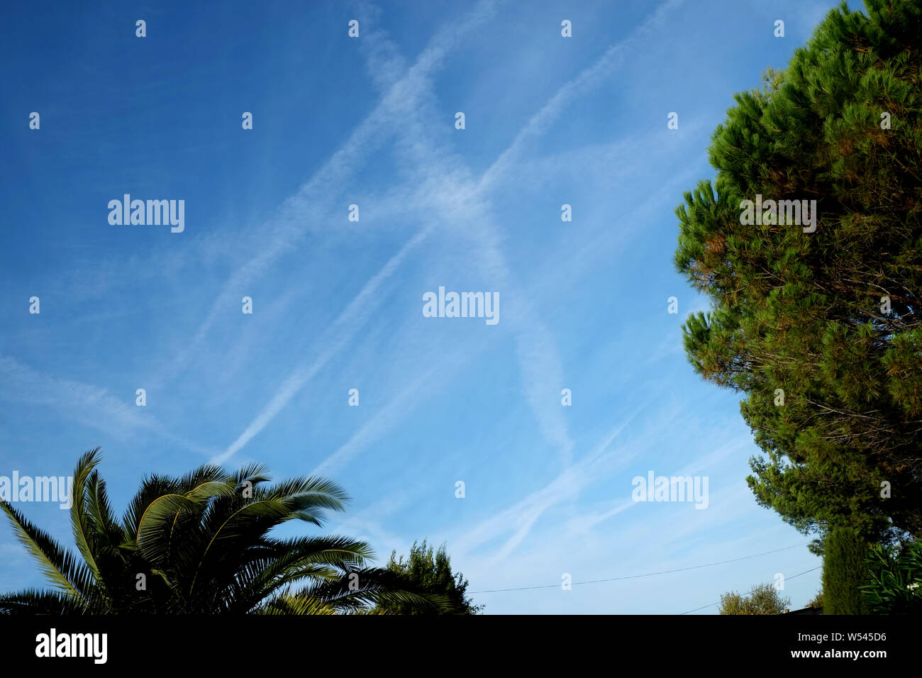 airplane trails in a blue sky in southern France showing how busy the area is with passing planes. A travel industry concept image. Stock Photo