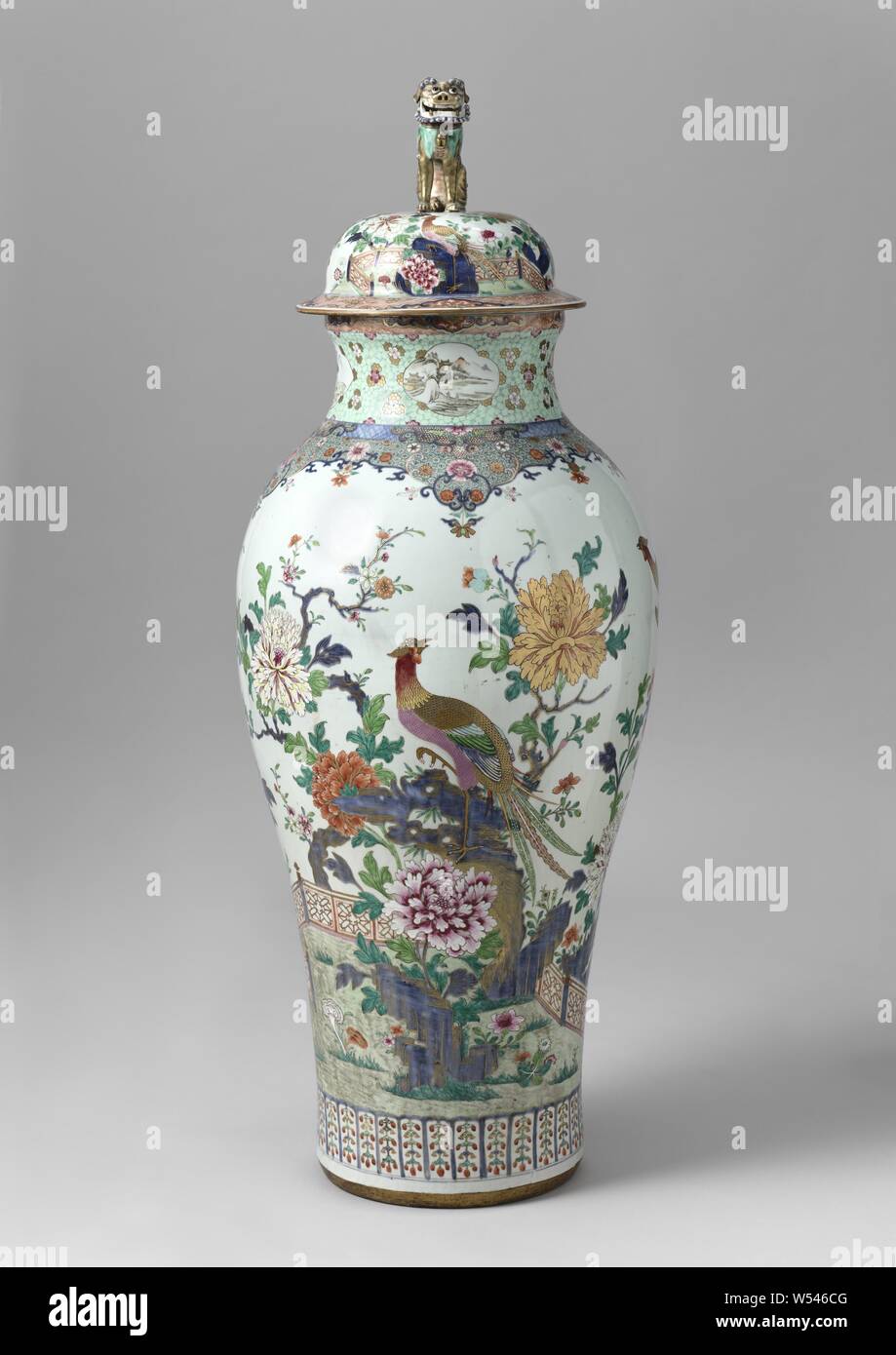Two Lidded Vases Baluster covered jar with pheasants on a rock near a fence and flowering plants, Baluster-shaped porcelain covered pot, painted in underglaze blue and on the glaze in blue, red, pink, green, yellow, black and gold. On the wall a pheasant on a rock with flowering plants (peony, prunus) and a fence. A second pheasant, butterflies and birds are flying in the sky. On the ground other flowers (aster, lotus, beautiful carnation), mushrooms (lingzhi) and a pond with ducks. On the shoulder a decorative band of small flower rosettes with curls and loose flowers. Above the foot a band Stock Photo