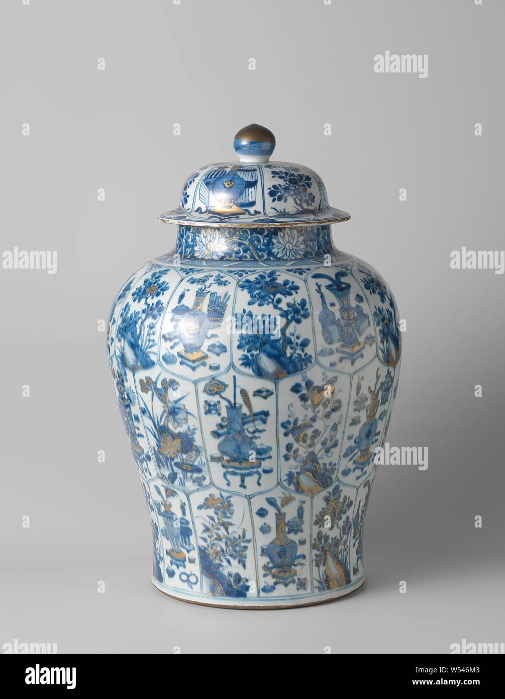 Baluster covered jar with flowering plants and auspicious symbols in panels, Baluster-shaped porcelain covered pot with a wide neck, painted in underglaze blue and on the glaze gold. The wall is divided into three rows with scalloped, rectangular compartments with alternating a flowering plant by a rock and lucky symbols and antiques. On the neck a band with lotus vines saved in a blue background. The bottom is unglazed. Blue and white with gold enamel, Jean Theodore Royer, anonymous, China, c. 1680 - c. 1720, Qing-dynasty (1644-1912) / Kangxi-period (1662-1722), porcelain (material), glaze Stock Photo