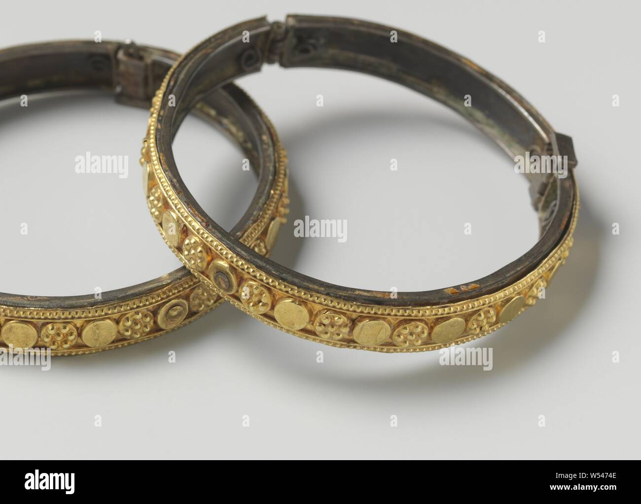 Pair of bracelets (chandan churi), Bracelet with a bronze inner ring with hinge and clasp, on which is attached a gold ring, decorated with turned-out circular ornaments and pearl borders., anonymous, Surat, c. 1750, gold (metal), bronze (metal), striking (metalworking), d 7.0 cm × h 0.9 cm Stock Photo