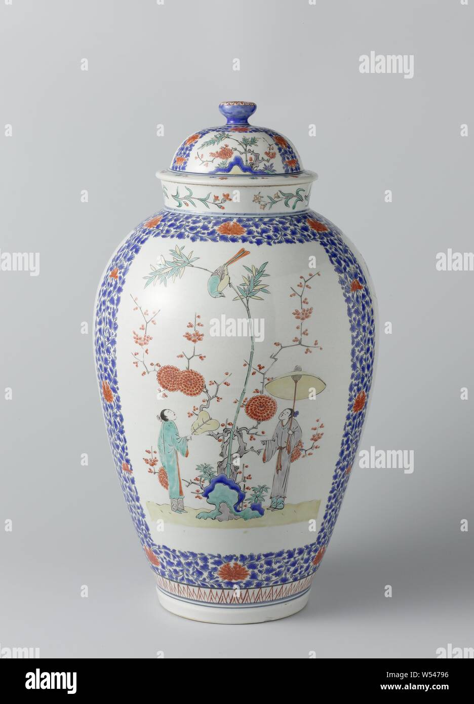 Lidded jar, Ovoid covered jar with figures, plants and birds, High, egg-shaped pot of porcelain, painted on the glaze in blue, red, green, yellow, eggplant and black. The belly is divided into three fields, always filled with two people with a fan and a parasol with flowering plants (bamboo, prunus) and a rock. The fields are enclosed by flower vines. Flower branches on the neck. The lid with the same decoration. Arita, Kakiemon style., anonymous, Japan, c. 1670 - c. 1690, Edo-period (1600-1868), porcelain (material), glaze, vitrification, h 53.3 cm d 15.8 cm d 28 cm d 16.2 cm Stock Photo