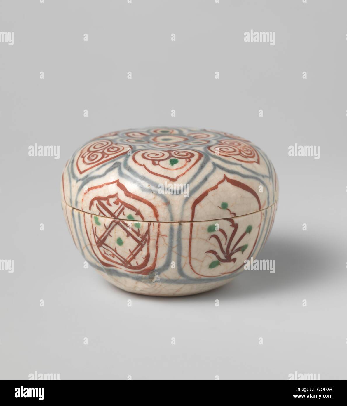 Box with diaper pattern and flowering plants in a panel decoration, Lid from a box of stoneware, painted in underglaze blue and on the enamel red and green. On the wall of the box, continuous on the lid, scalloped cartouches with alternating napkin work or a flowering plant. The top of the lid with a flower rosette surrounded by a band with a kind of ruyi motifs. Decoration following the Chinese kraak porcelain., anonymous, Vietnam, c. 1400 - c. 1600, stoneware, glaze, cobalt (mineral), vitrification, h 1.8 cm × d 7.2 cm Stock Photo