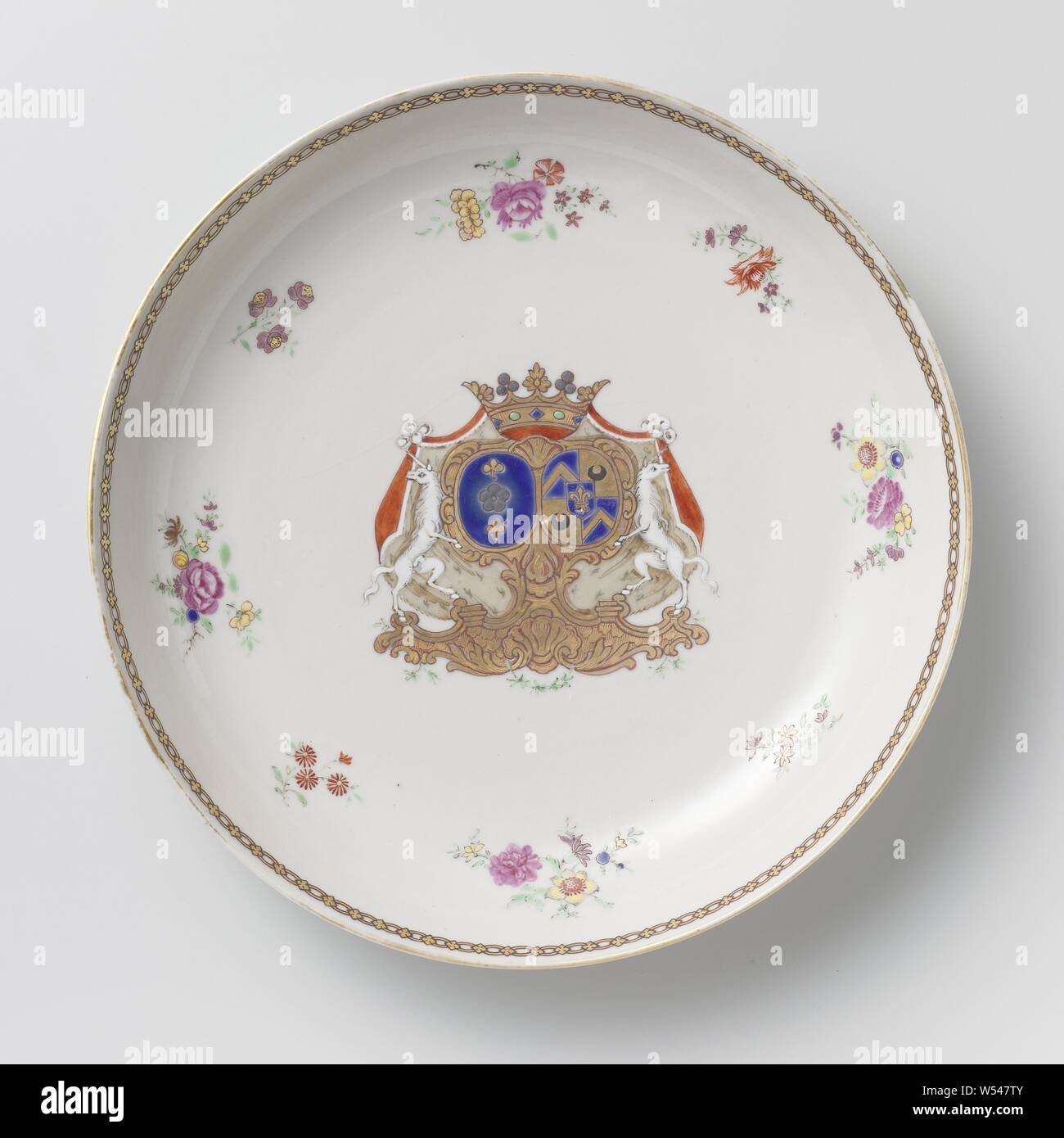 Saucer-dish with the arms of the Van Idsinga and Kien families, Porcelain plate, painted on the glaze in blue, red, pink, green, yellow, purple, black and gold. On the flat the alliance weapon of the Van Idsinga and Kien families. The coat of arms to the left of the Van Idsinga family has a blue background with a silver rose or flower and a pair of golden clovers. The weapon to the right of the Kien family is divided into four parts: 1. and 4. a blue background with a golden twill, 2. and 3. a golden background with a black moon. In the center of the weapon is a heart shield with a blue Stock Photo