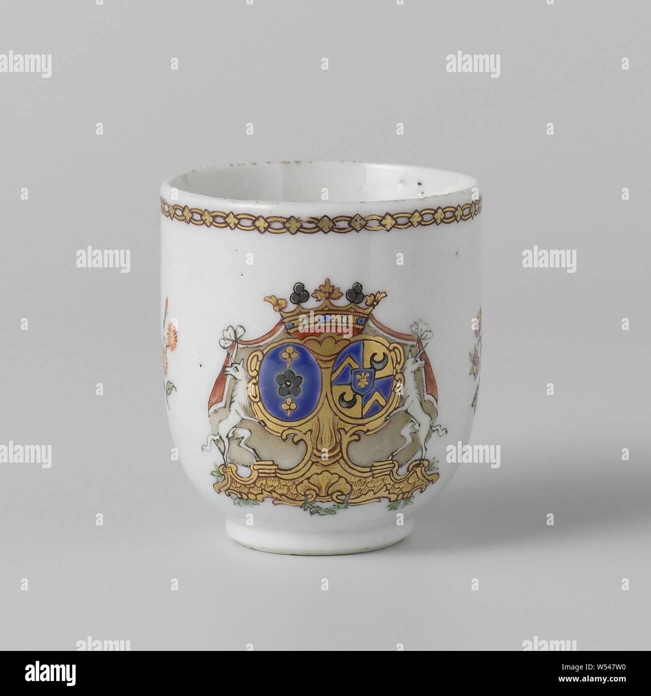 Cup with handle with the arms of the Van Idsinga and Kien families, Porcelain ear cup, painted on the glaze in blue, red, pink, green, yellow, purple, black and gold. On the wall the alliance weapon of the Van Idsinga and Kien families. The coat of arms to the left of the Van Idsinga family has a blue background with a silver rose or flower and a pair of golden clovers. The weapon to the right of the Kien family is divided into four parts: 1. and 4. a blue background with a golden twill, 2. and 3. a golden background with a black moon. In the center of the weapon is a heart shield with a blue Stock Photo