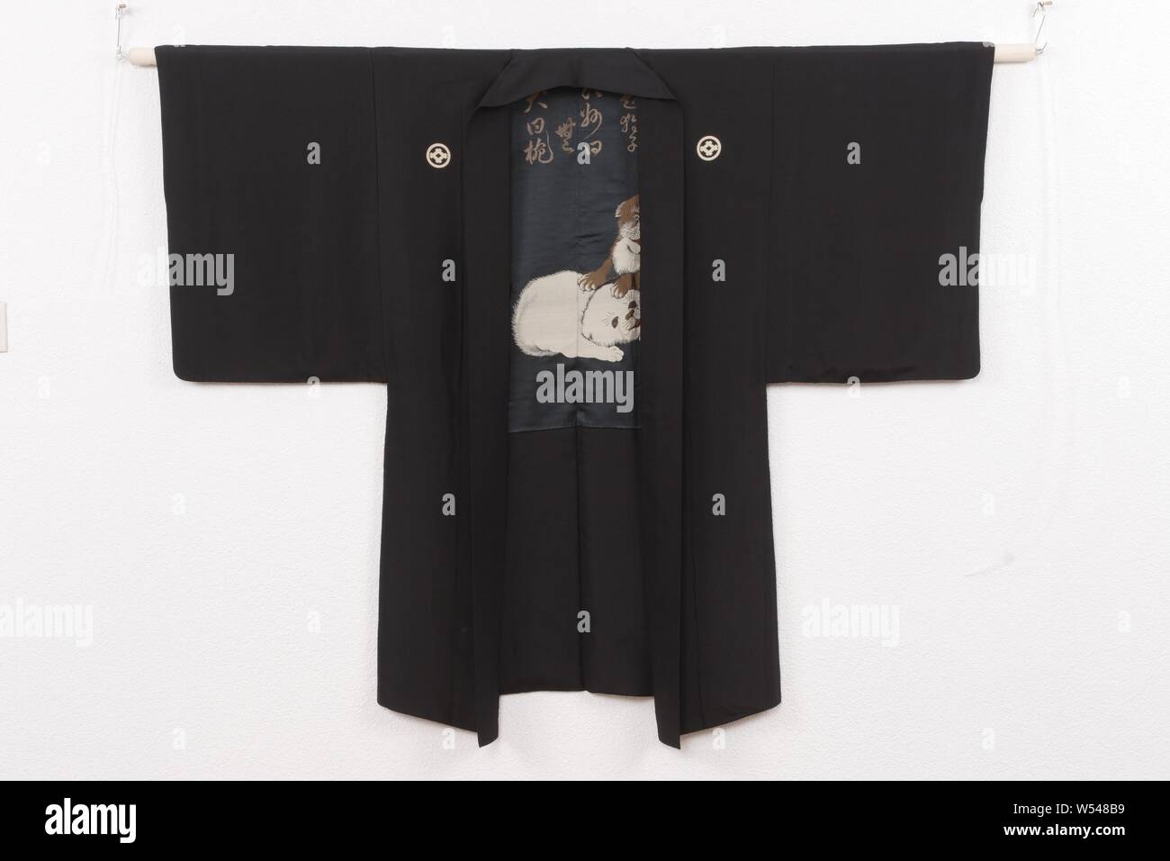 Men haori with poem and three young dogs, Haori for a man with a decoration on the lining of three playing young dogs, two brown and one white, with a poem above it by the priest Shaku Soen (1859-1919): 'Dai kushi, Joshu iwaku mu, inu iwaku wan' (About the puppy, Joshu says 'no', the dog says 'waf'), signature 'Ryogakutsu Soen', seal 'En'. It is a reference to the question of the Chinese zen priest Joshu (778-897) 'kushi bussho' ('has a puppy the Buddha nature'), to which he answered 'mu' ('non-something'). The 'waf' of the dog, 'wan' is written with the character for soup bowl, also 'wan', as Stock Photo