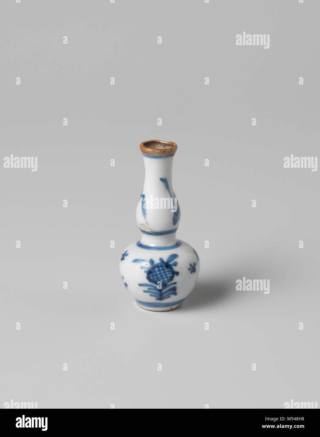 Miniature double-gourd-shaped vase with flowering plants, Miniature porcelain vase with gourd-shaped body, painted in underglaze blue. A flowering plant twice on the belly and neck, the edge with a brown glaze. Blue White., anonymous, China, c. 1675 - c. 1724, Qing-dynasty (1644-1912) / Kangxi-period (1662-1722) / Yongzheng-period (1723-1735), porcelain (material), glaze, cobalt (mineral), vitrification, h 6 cm d 0.8 cm d 3 cm d 1.6 cm Stock Photo