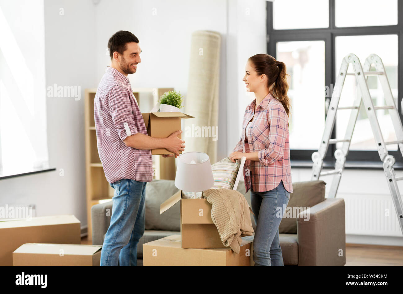 happy couple with stuff moving to new home Stock Photo - Alamy