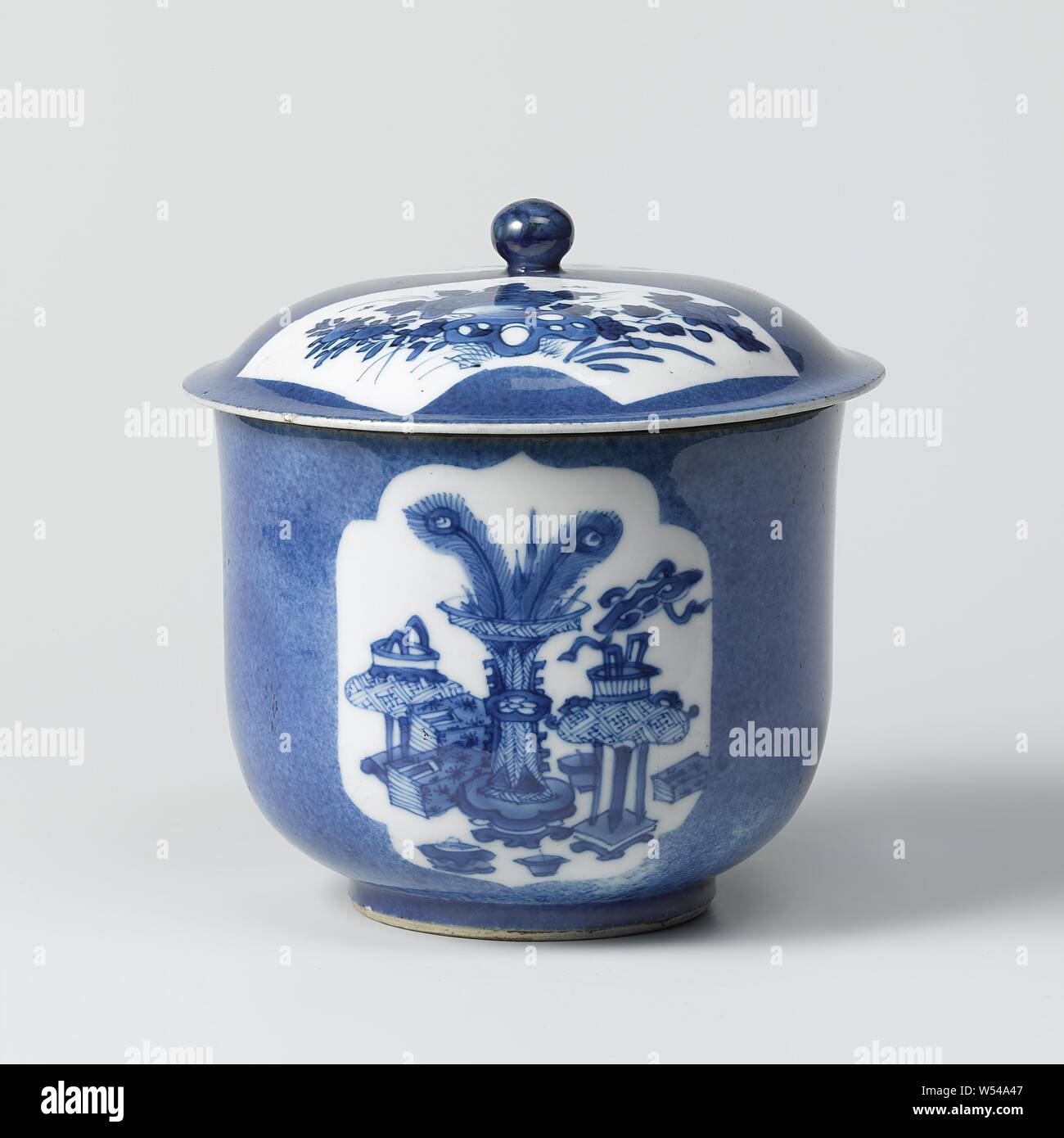Lid or covered jar, On the lid two recessed, fan-shaped boxes with flowering plants near a rock. Blue poudré with blue and white., anonymous, China, c. 1700 - c. 1720, Qing-dynasty (1644-1912) / Kangxi-period (1662-1722), porcelain (material), glaze, cobalt (mineral), vitrification, h 4.5 cm × d 15.7 cm Stock Photo