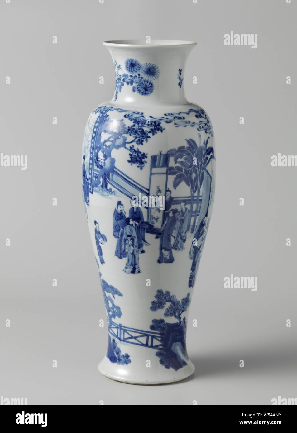 Baluster vase with four groups of scholars in a fenced garden, Baluster shaped porcelain vase with spreading base, wide neck and trumpet-shaped mouth, painted in underglaze blue. On the wall a continuous representation of four groups of scholars in a fenced garden: a group is writing at a table, with a large screen behind them, a second group plays 'go' at a table, a third group sits in front of a screen at a table, the screen is decorated with swirling water, they listen to the person who is playing on the 'qin', the fourth group admires a hanging role that is being held by a clerk. Rocks Stock Photo