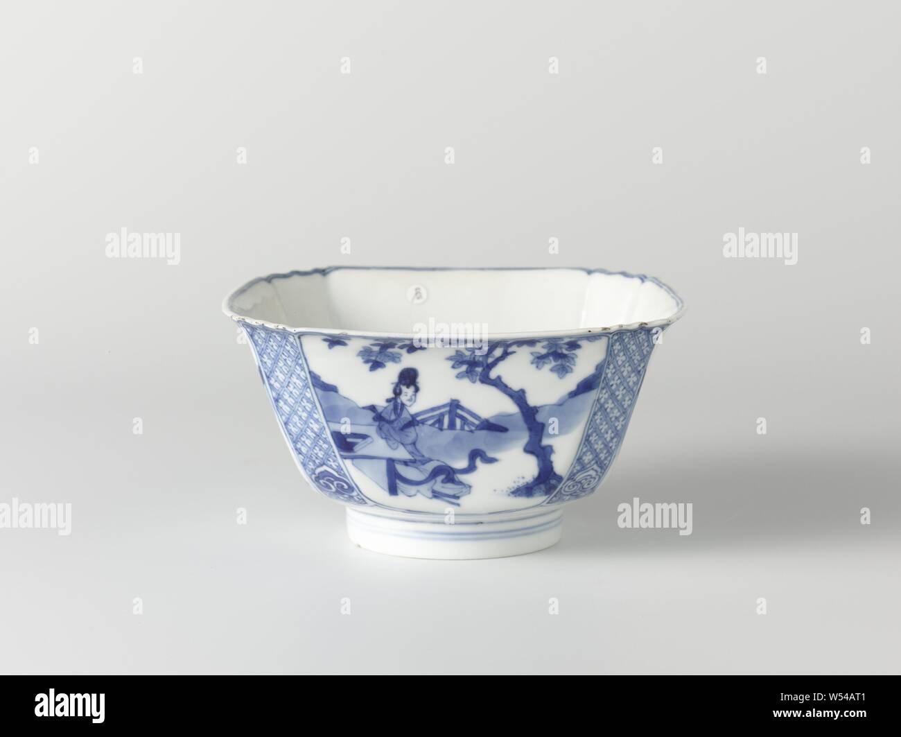Square bowl with Chinese ladies in a landscape, Square bowl of porcelain with flattened corners and scalloped edge, painted in underglaze blue. On the walls a Chinese lady (long list) in a landscape by a tree (banana plant, pine, willow, paulownia). Napkin work with a ruyi motif on the corners. At the bottom a square cartouche with squeezed corners with three dancing boys (crazy people) in a landscape. Marked on the underside with the six-character mark of Emperor Chenghua in a double circle. Blue White., anonymous, China, c. 1680 - c. 1720, Qing-dynasty (1644-1912) / Kangxi-period (1662-1722 Stock Photo