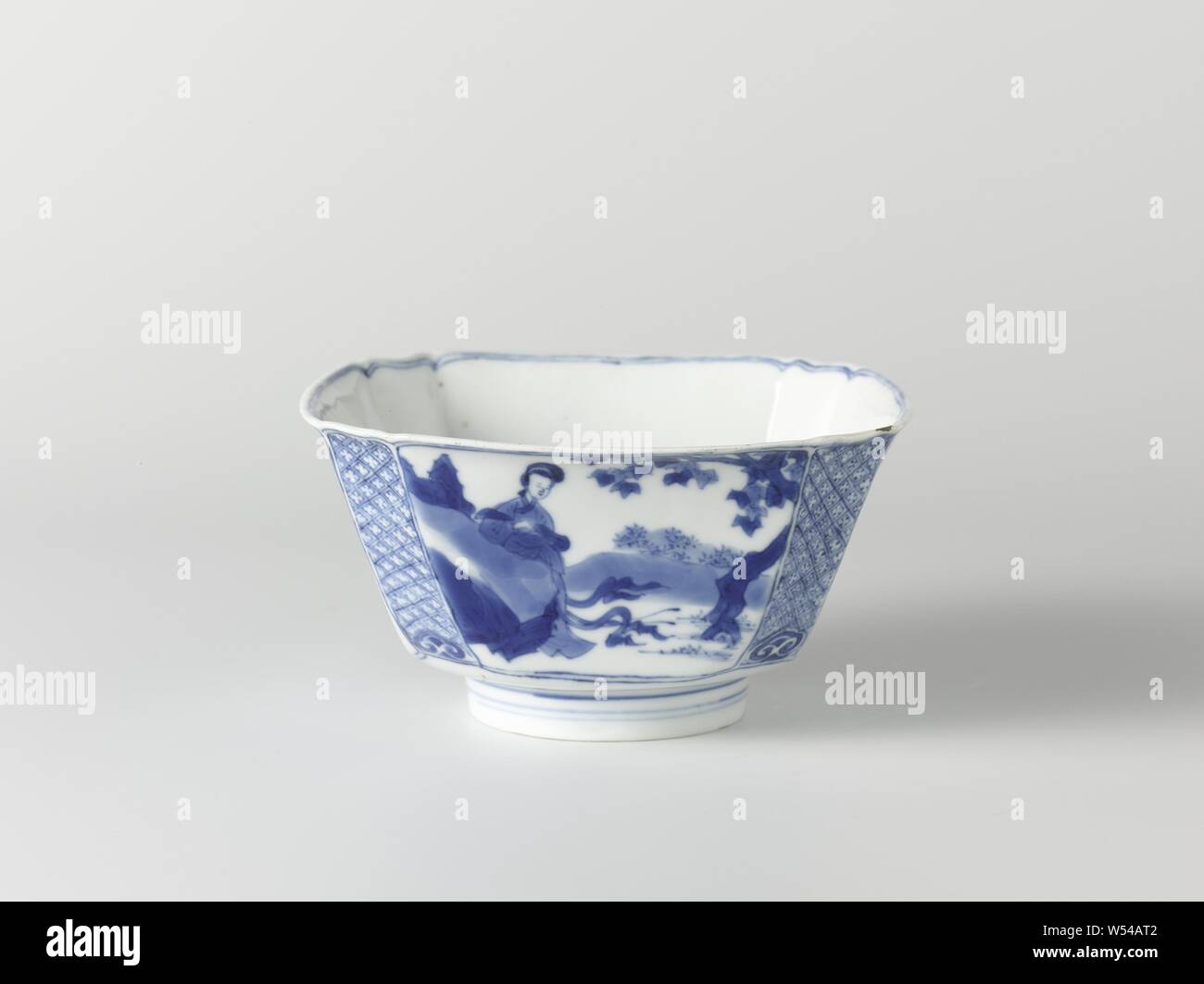 Square bowl with Chinese ladies in a landscape, Square bowl of porcelain with flattened corners, painted in underglaze blue. On the walls a Chinese lady (long list) in a landscape by a tree (banana plant, pine, willow, paulownia). Napkin work with a ruyi motif on the corners. At the bottom a square cartouche with squeezed corners with three dancing boys (crazy people) in a landscape. Marked on the underside with the six-character mark of Emperor Chenghua in a double circle. Blue White., anonymous, China, c. 1680 - c. 1720, Qing-dynasty (1644-1912) / Kangxi-period (1662-1722), porcelain Stock Photo