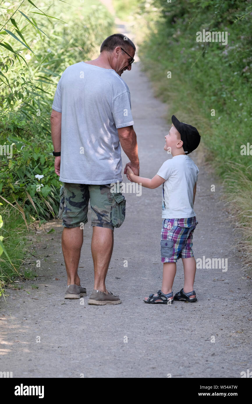 A young boy and grand parent share a moment of fun whilst out on a nature trail walk in the countryside Stock Photo