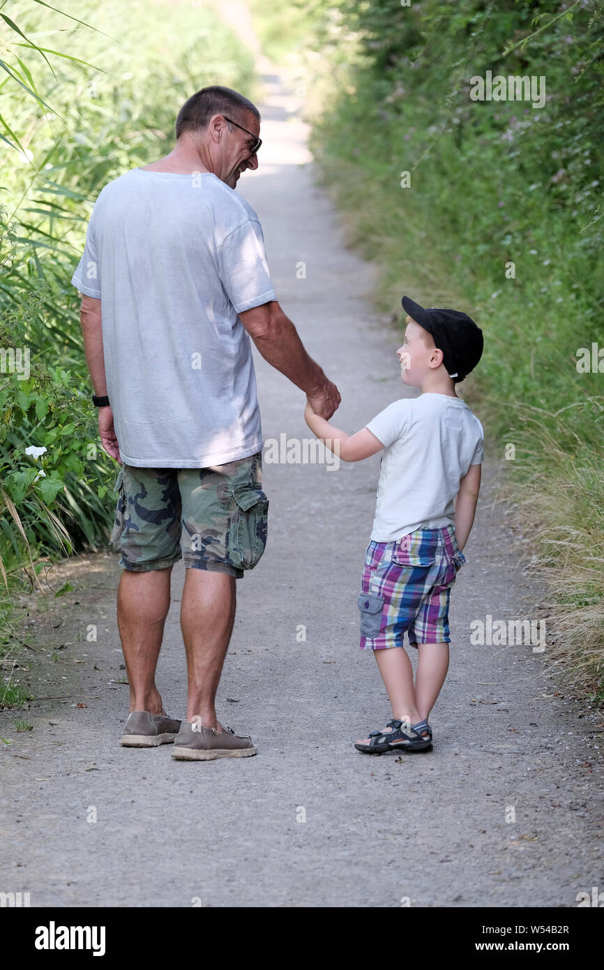 A young boy and grand parent share a moment of fun whilst out on a nature trail walk in the countryside Stock Photo