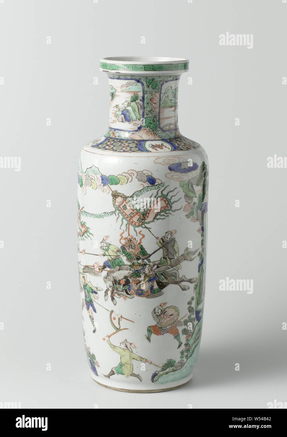 Vase with pine, battle scene and two river landscapes, Porcelain vase with cylindrical body, flat shoulder and cylindrical neck with raised edge, painted on the glaze in blue, red, green, yellow, eggplant, black and gold. On the wall a continuous representation with a large pine tree and a battle with armed warriors with flags, on foot and on horseback, on the shoulder a geometric motif alternated with four cartouches with valuables (books, music stone, horns), the neck with lotus flowers on a black dotted green ground with two cartouches with river landscape in reserve, a meander pattern Stock Photo