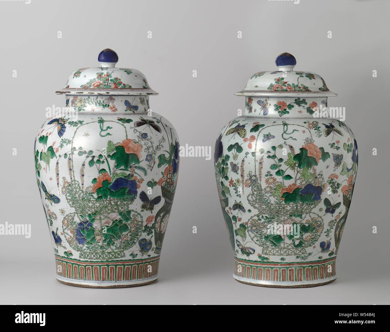 Baluster covered jar with flower baskets, flower sprays and insects, Baluster-shaped porcelain covered pot, painted on the glaze in blue, red, green, yellow, aubergine, black and gold. On the belly four times a flower basket with aster, peony, prunus, blue rain, lotus, chrysanthemum and iris. One basket with shishi and ruyi motifs and one basket with feng huangs and Chinese characters. Separate flower sprays and insects between the baskets. Above the foot a band with stylized leaf motifs. On the shoulder a strap with hatching. The neck with flower sprays and butterflies. A crack in the rim Stock Photo