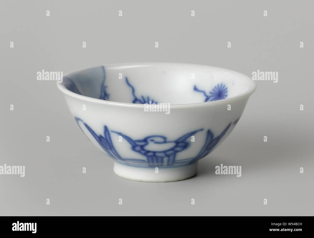 Bell-shaped bowl with a water landscape and stylized lotuses, Bell-shaped porcelain cup, painted in underglaze blue. On the outside wall a continuous band with stylized lotus plants with alternately a flower and a bird on a leaf. The inside with a continuous landscape with pavilions, people and a pine tree near a rock. Marked on the bottom with two unidentified Chinese characters in a circle. Blue White., anonymous, China, c. 1680 - c. 1720, Qing-dynasty (1644-1912) / Kangxi-period (1662-1722), porcelain (material), glaze, cobalt (mineral), vitrification, h 2.6 cm d 5.7 cm Stock Photo