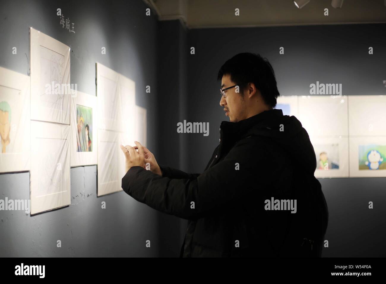 A visitor takes photos of manuscripts of Japanese manga series One Piece on display during a Japanese animation manuscript exhibition in Shanghai, Chi Stock Photo