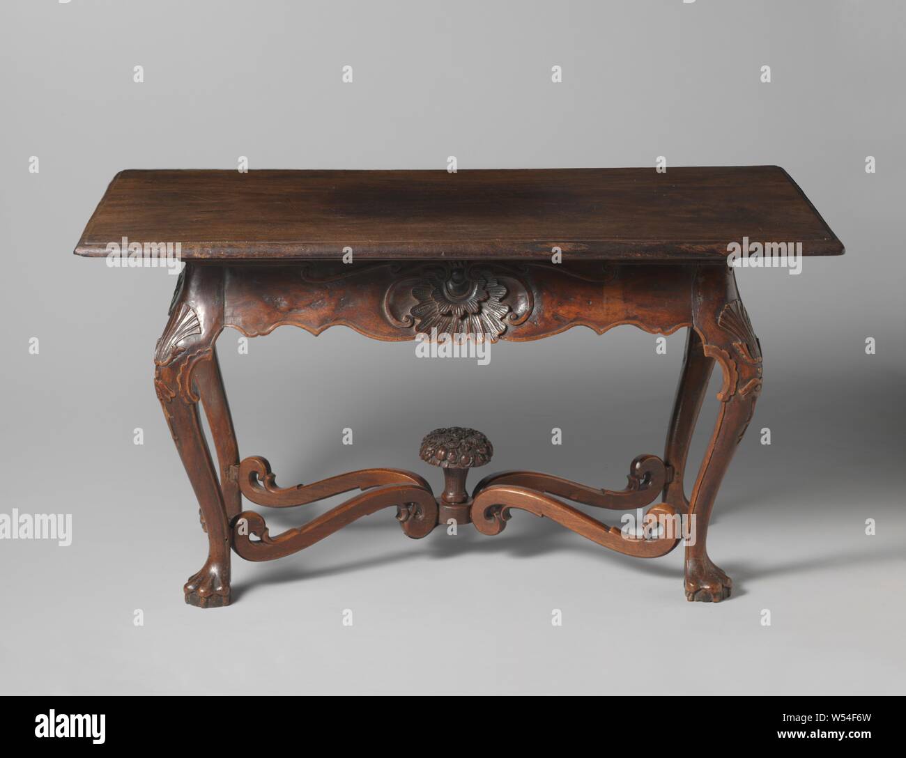 Table made of Indonesian wood, resting on S-shaped legs placed at an angle, ending in convex claws and adorned with a carved shell pattern above the swelling. The legs are connected by an X-shaped cross, formed by S-shaped rungs with a flower basket at the intersection. The lines are scalloped on the bottom and have carved shell motifs, flanked by volutes, as center pieces. The far-reaching leaf is of a different type of wood, probably not originally., anonymous, Indonesia, c. 1720 - c. 1740, wood (plant material), teak (wood), h 81 cm × w 153 cm × d 89 cm × w 64 kg Stock Photo