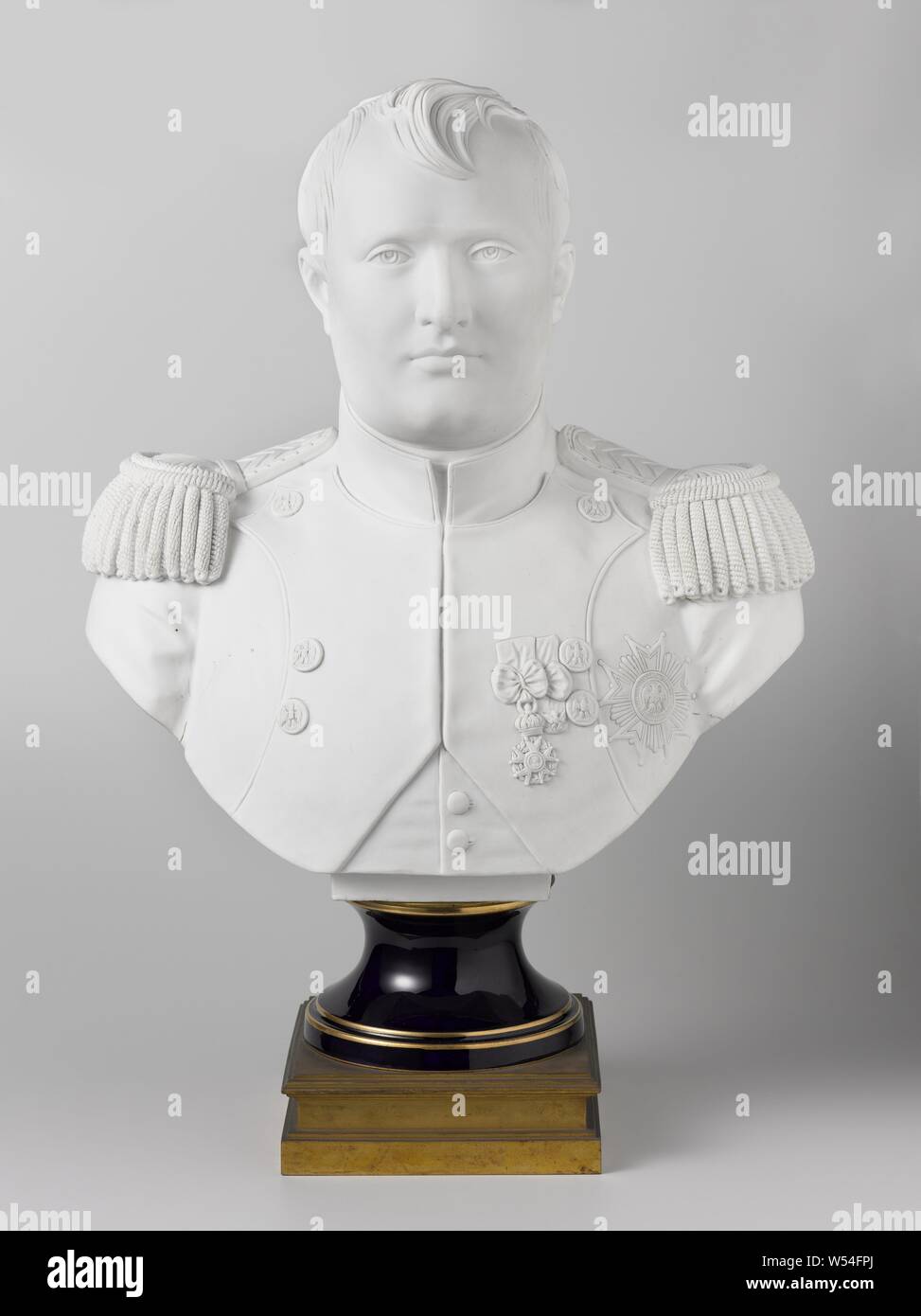Bust of biscuit, representing Napoleon Bonaparte, Bust portrait in biscuit representing the porcelaine Napoleon Bonaparte on a pedestal of dark blue glazed porcelain with golden piping, bearing the mark : manufacture Imperiale de Sevres chopped in red letters above the glaze. Above is a round copper closing plate. Under the base a profiled square copper base. Napoleon is bareheaded and looks straight ahead. He wears the well-known military clothing with epaulettes and three order signs. On the reverse side is engraved with poorly cared for letters Mre. Imple de Sevres. Bust officiel de Stock Photo