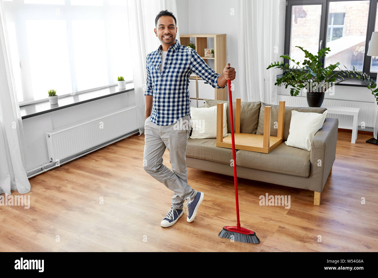 man with broom cleaning floor at home Stock Photo
