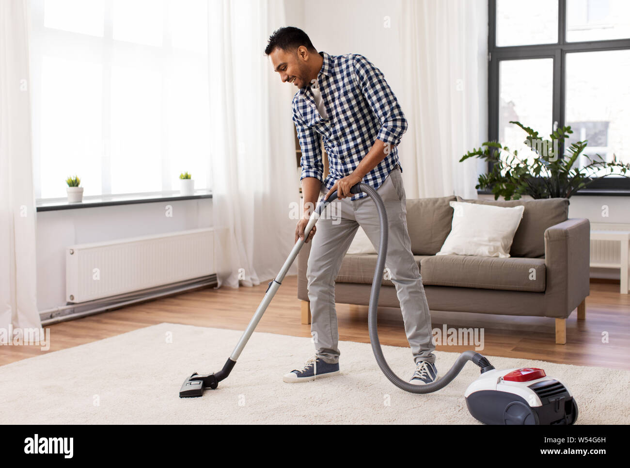 indian man with vacuum cleaner at home Stock Photo Alamy