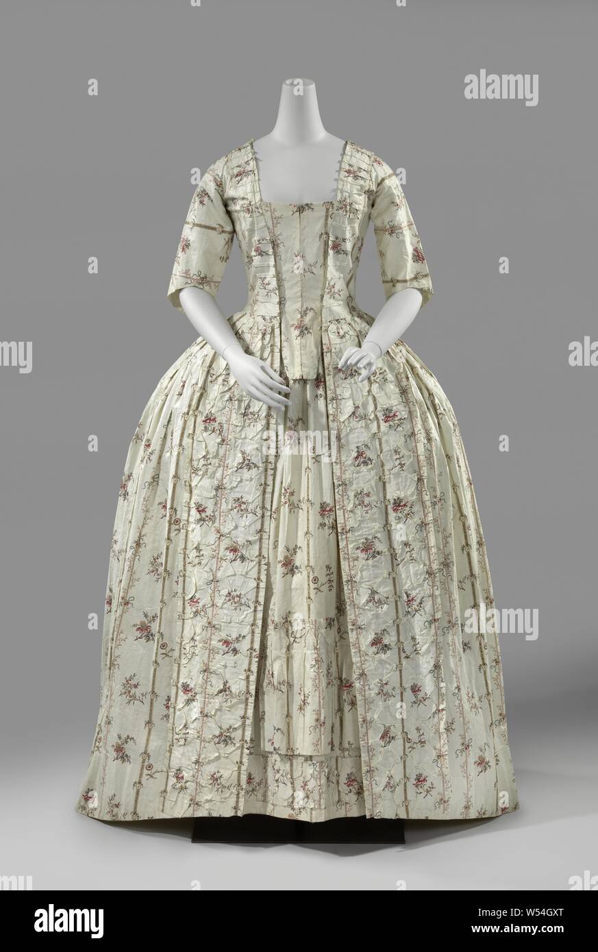 Dress Made of Printed Fabric, Overjapon belonging to a women's suit of printed cotton (chintz) with a pattern of stripes and bouquets. Open at the front with a small drag. Row body lined with white linen. Wide angular neck. For close fitting and with two vest buildings and long skirts. Behind bell folds. Half sleeves. Opening and neck are trimmed with a pleated strip. Along the skirt hem a lining strip of white linen., anonymous, Netherlands, 1775 - 1785, cotton (textile), linen (material), chintz, l 36.0 cm Stock Photo