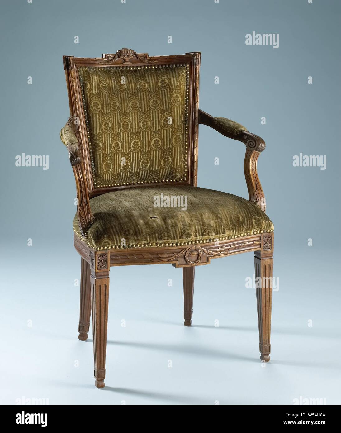 Chair of mahogany, covered with string with a continuous pattern of oval hanging flowers in which a flower on striped ground, covered with string with a continuous pattern of oval hanging flowers in which a flower on a striped ground. The square legs are fluted. The front line is decorated in the middle with a laurel wreath and a pendulum. The back frame is parallelogram-shaped and concave. The upper threshold is decorated with a stabbed vase and laurel garland. The cover is attached with nails with gold-plated heads. The chair belongs to an ameublement, anonymous, Northern Netherlands, 1775 Stock Photo