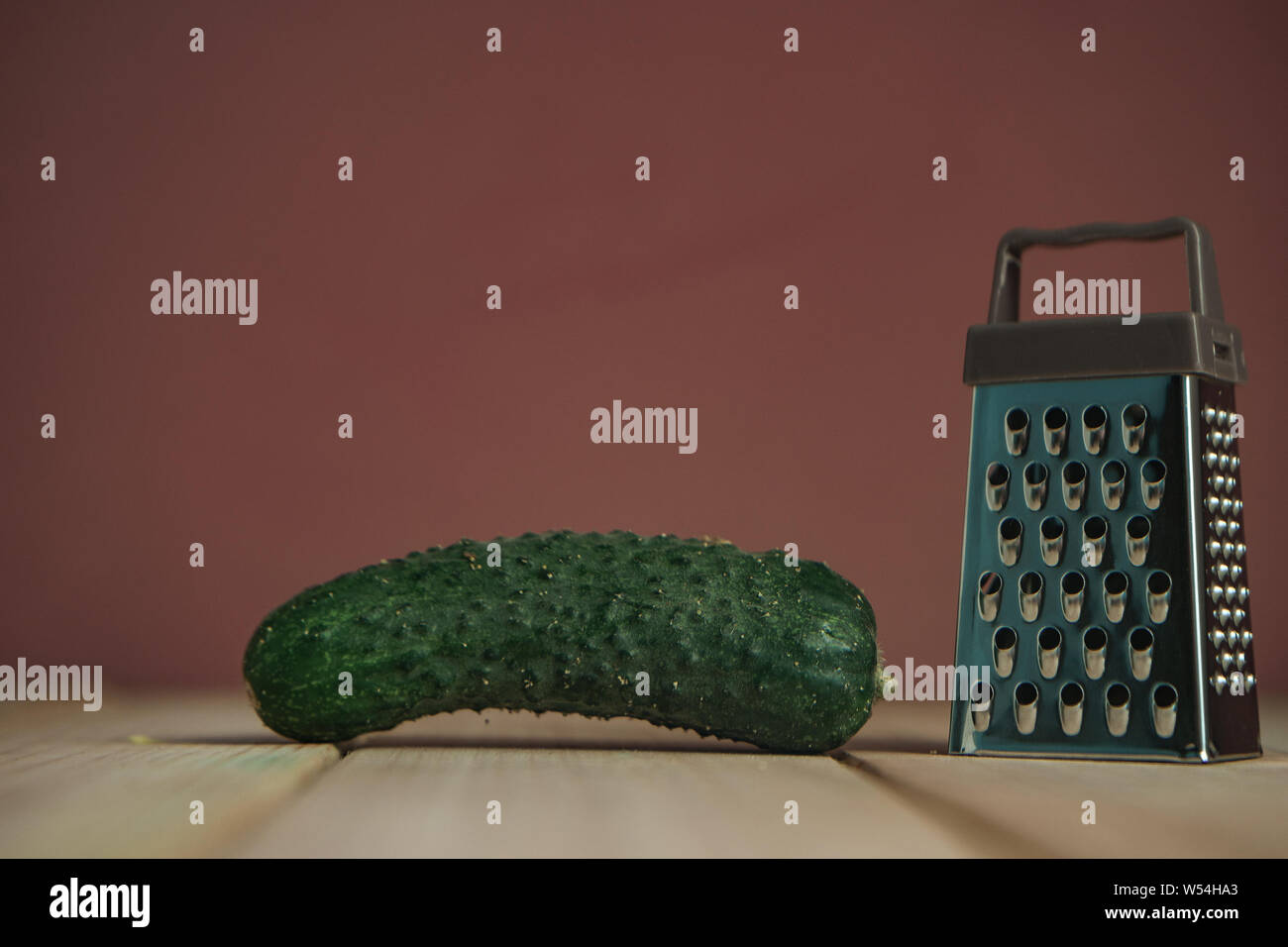 Close up beautiful new grater on a wooden table, brown wall background. Stock Photo