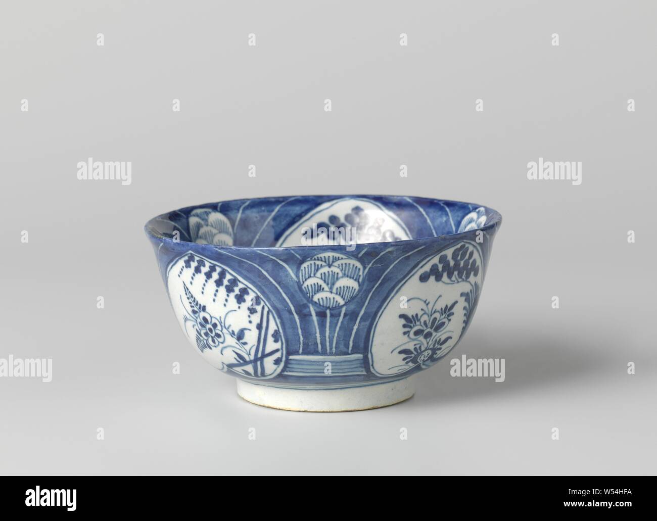 Bowl of faience, blue decorated. On the inside and outside, respectively, decorated with three and four so-called heart motifs that are filled with flowers and leaves., De Dubbele Schenkkan, Delft, c. 1688 - c. 1715, d 11.5 cm × h 5.5 cm Stock Photo
