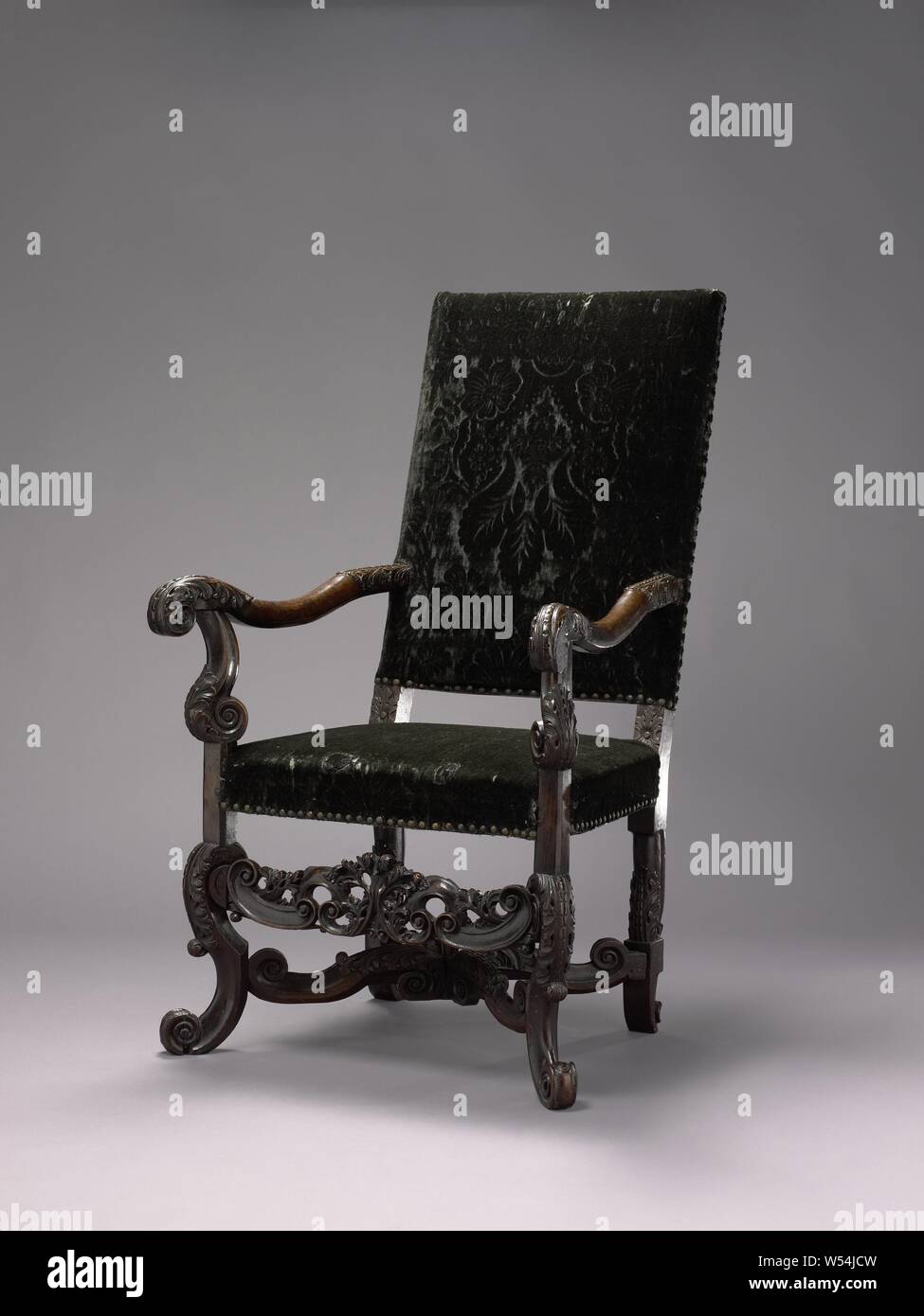 Armchair on angled front legs in the form of broken S-volutes, decorated with acanthus leaves. Back window rests on struts with rosettes, Armchair made of walnut. The furniture is upholstered and rests on angled front legs in the shape of broken S-volutes, decorated with acanthus leaves. The legs are connected by an X-shaped cross, also with broken S-volutes and acanthus leaf. The armrest struts are S-shaped, the armrests are slightly concave and end in a volute with acanthus leaf. The high back window rests on struts with rosettes., anonymous, Netherlands (possibly), c. 1695 - c. 1705, wood Stock Photo
