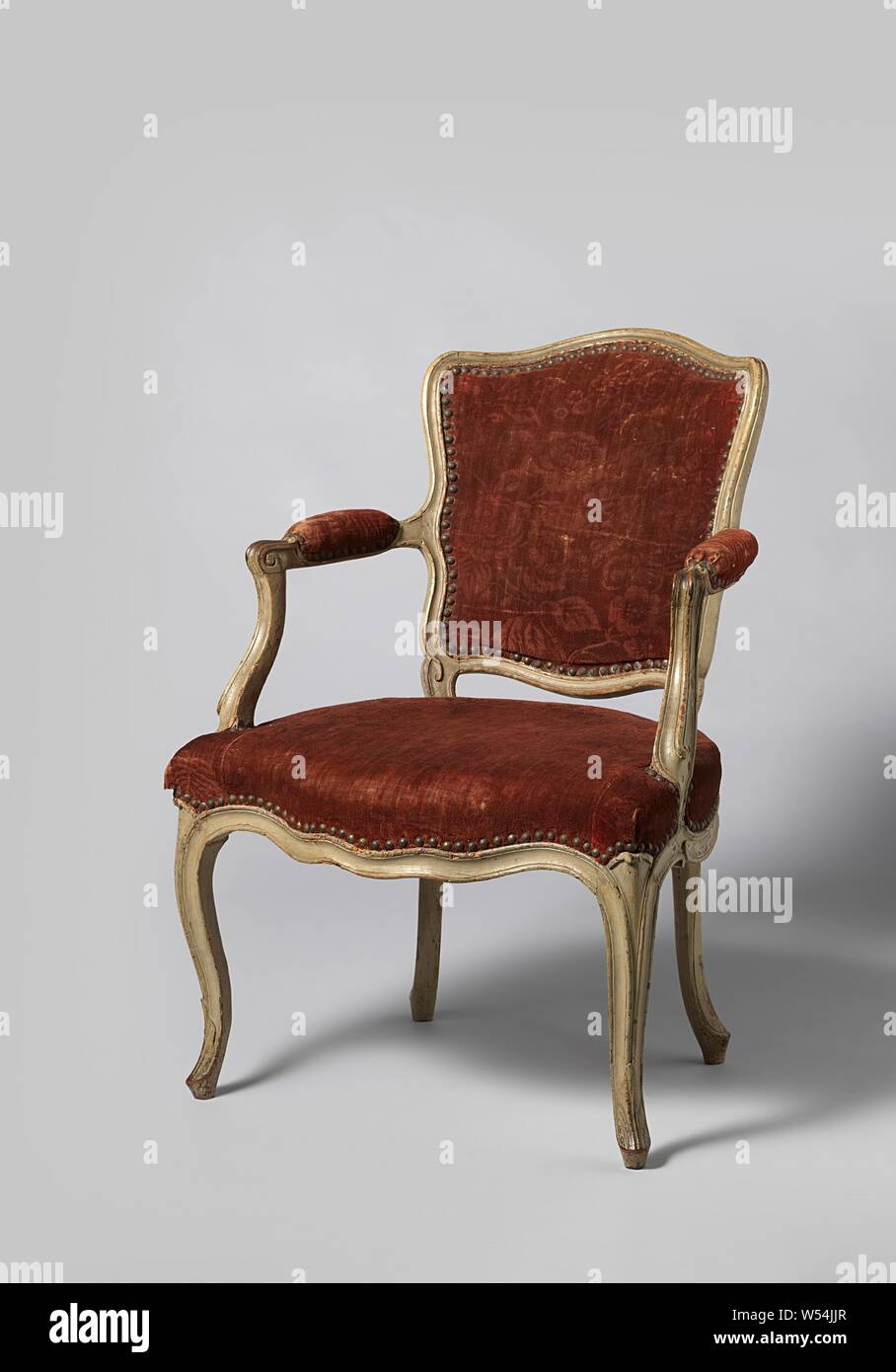 Armchair on S-shaped curved front legs, painted gray walnut and covered with red velvet with rose branch pattern, Armchair made of gray painted walnut with red nailed velvet with a rose branch pattern. The S-shaped front legs, placed at an angle, merge into the scaled seat lines without interruption. The trapezoidal seat is slightly curved at the front and curved at the sides. The armrests recede outwards, have pads and end in volutes. The armrest struts merge into the armrests in an S-shape. The back window rests on small struts, slightly curved styles and sills., anonymous, France, 1750 Stock Photo