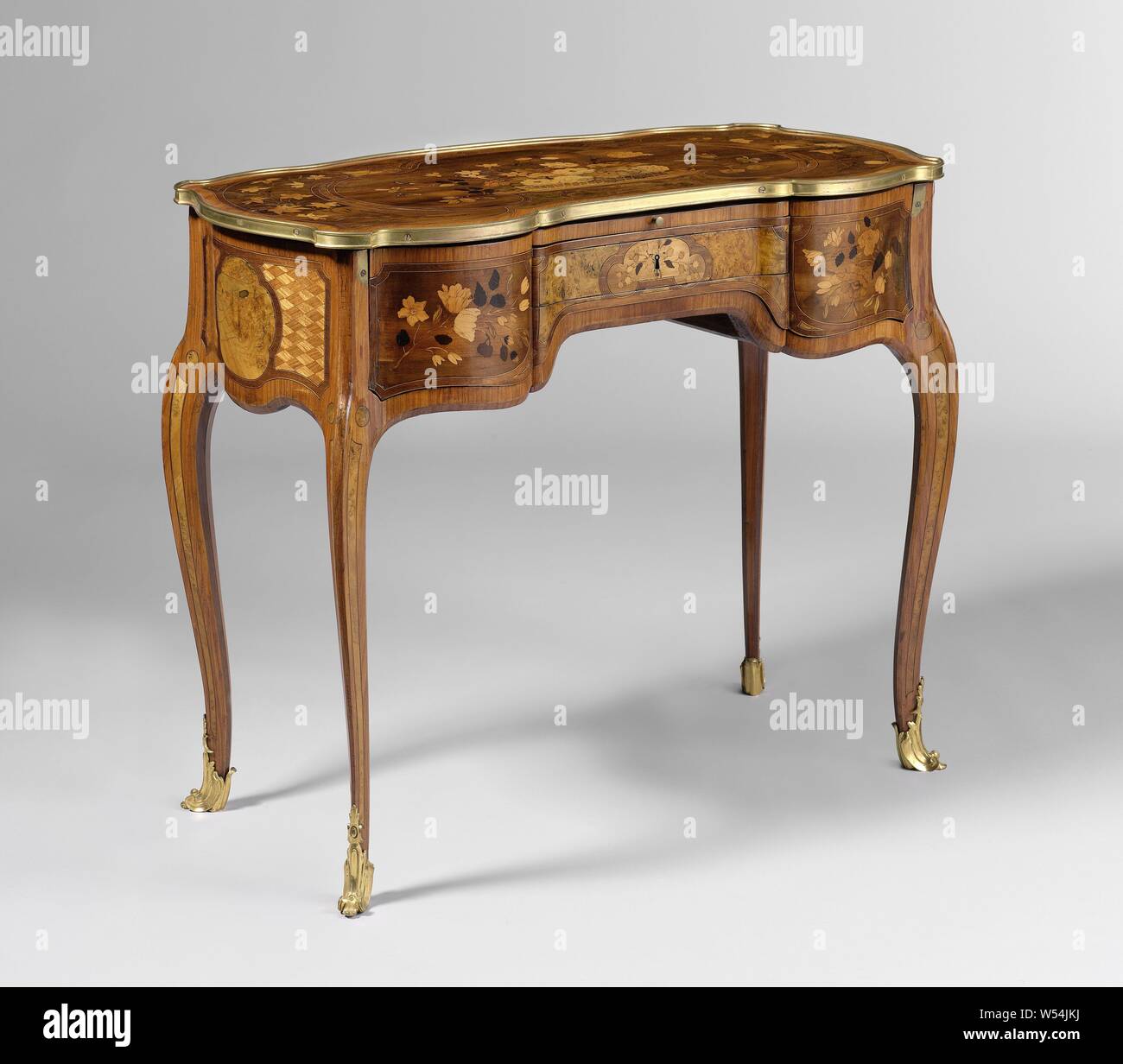 Writing and dressing table, Table glued with multiple types of wood on an oak core, with gilt bronze fittings. The stretched S-shaped legs placed diagonally overflow into the scalloped lines. The front bar contains a concave, recessed drawer and convex side pieces in the middle and is fully extendable, above the drawer a foldable top with mirror. The lines and the sheet show fields with bandwork, on the front line and the leaf with floral motifs and on the side lines with four-pass and braid motifs, ornaments, art, Jean François Oeben, Paris, c. 1762 - c. 1768, wood (plant material), oak (wood Stock Photo