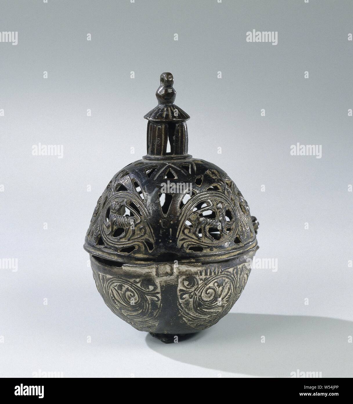Censer, spherical, Consisting of two hemispheres, the container on a (indented) round base with three legs, the ajour-worked lid with a lantern, with four openings and an eye on top. On both parts on the outside two eyes (originally three), to confirm the currently missing chain. The decoration on the container and lid consists, among other things, of three equally worked-out ball segments, distributed over both. They are decorated with symmetrical tendrils, the stems of which are composed of three ribs, which split, multiply and end in leaf motifs. The upper halves on the lid are provided Stock Photo