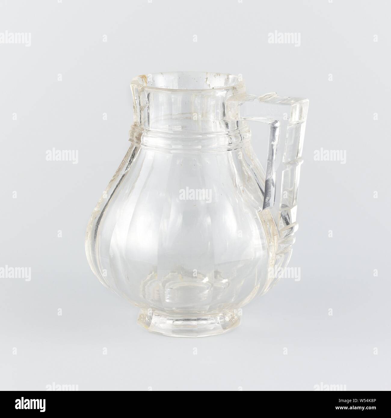 Ewer, Jug, sharpened in twelve vertical facets, Jug made of rock crystal with gold-plated silver frames. The pear-shaped vessel is ground in twelve vertical facets. A convex profile runs around the neck. The square rectangular section has three protrusions. Landscapes are engraved on the frame of the foot and neck. The lid, which is also cut in twelve facets, is crowned with a lion's head in gold-plated silver., anonymous, Zuid-Italie (possibly), c. 1350, silver (metal), gilding, h 17.0 cm × w 15.9 cm × d 14.5 cm d 7.3 cm Stock Photo