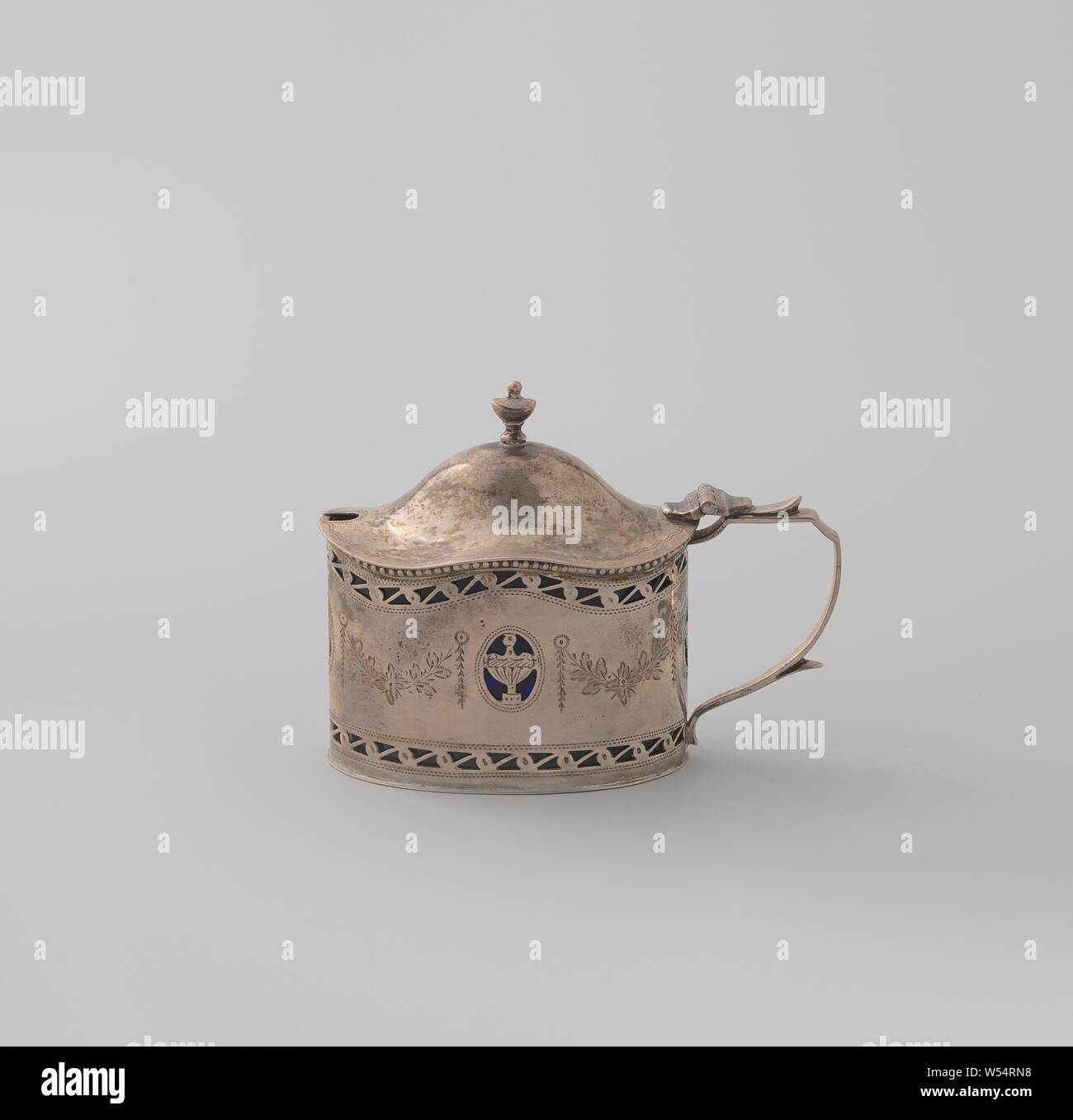Mustard pot, Oval mustard pot of silver, in Louis XVI style. With a corrugated top edge and a curved lid. An openwork edge along the top and bottom., anonymous, London, 1908 - 1909, silver (metal), binnenpot, h 8.0 cm × l 8.0 cm × w 5.3 cm Stock Photo