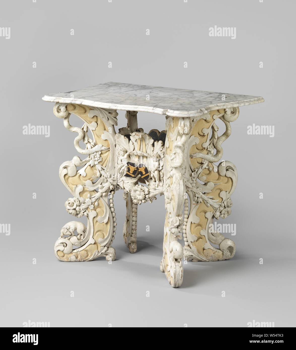 Table painted in white with four angled legs and carved, Table in white painted lime with four angled legs, made up of two C-volutes placed one above the other. The legs are decorated with acanthus leaves and on the back with pearl cords. At the bottom there is a dog, at the top a snake. The flat connecting line has a standing acanthus leaf at the front, for which a double coat of arms (each with a cow's head with a beam) in the middle of two putti. At the bottom a flower garland, which splits into two on the legs. Marble top., anonymous, Northern Netherlands, 1650 - 1700, wood (plant material Stock Photo