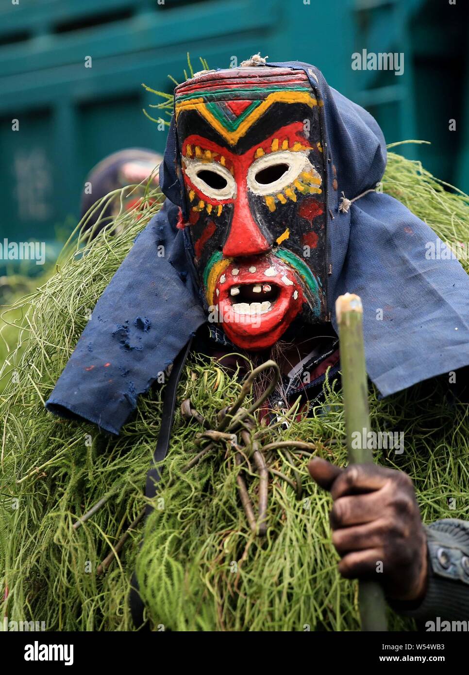 Chinese people of Miao ethnic group wearing masks and grassy cloaks dress up as the god to bring good luck to villagers during the Manggao Festival in Stock Photo