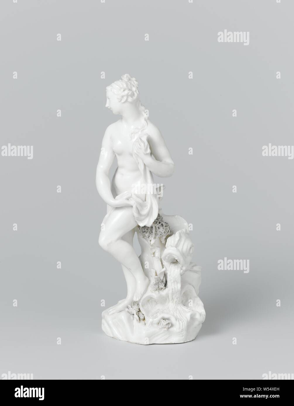 Venus, Figure, depicting Venus with a dress in her hands, leaning against a rock with a dolphin, a shell and water plants, (story of) Venus (Aphrodite), Weesper porseleinfabriek, Weesp, 1764, porcelain (material), h 20.3 cm × w 8.3 cm × d 9.1 cm w 7.4 cm × d 7.8 cm Stock Photo